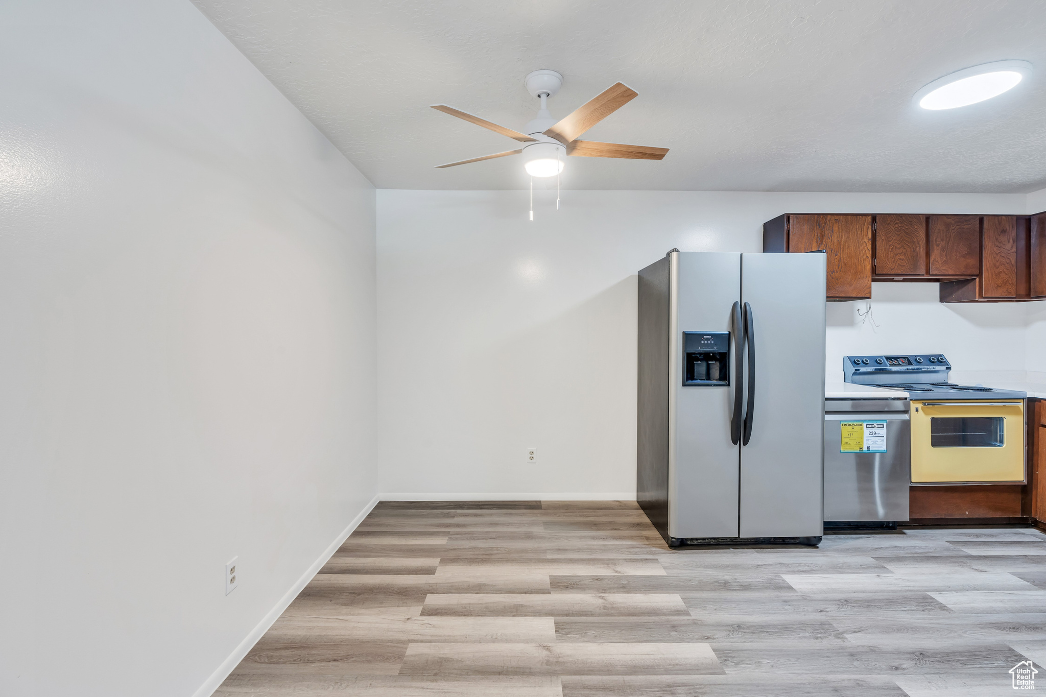 Kitchen with stainless steel appliances, ceiling fan, and light hardwood / wood-style floors