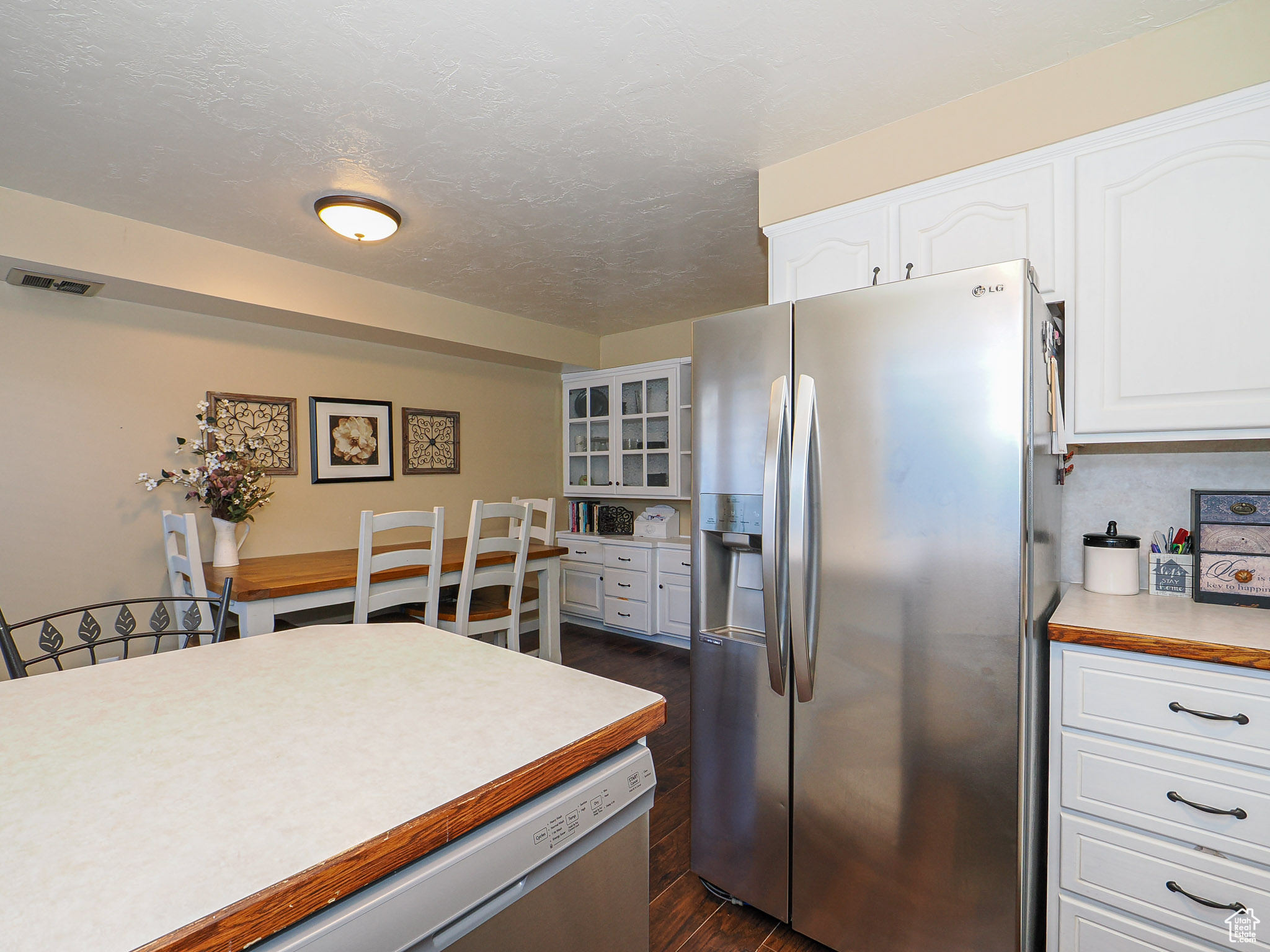 Kitchen featuring dark hardwood / wood-style floors, white cabinets, a textured ceiling, and stainless steel fridge with ice dispenser