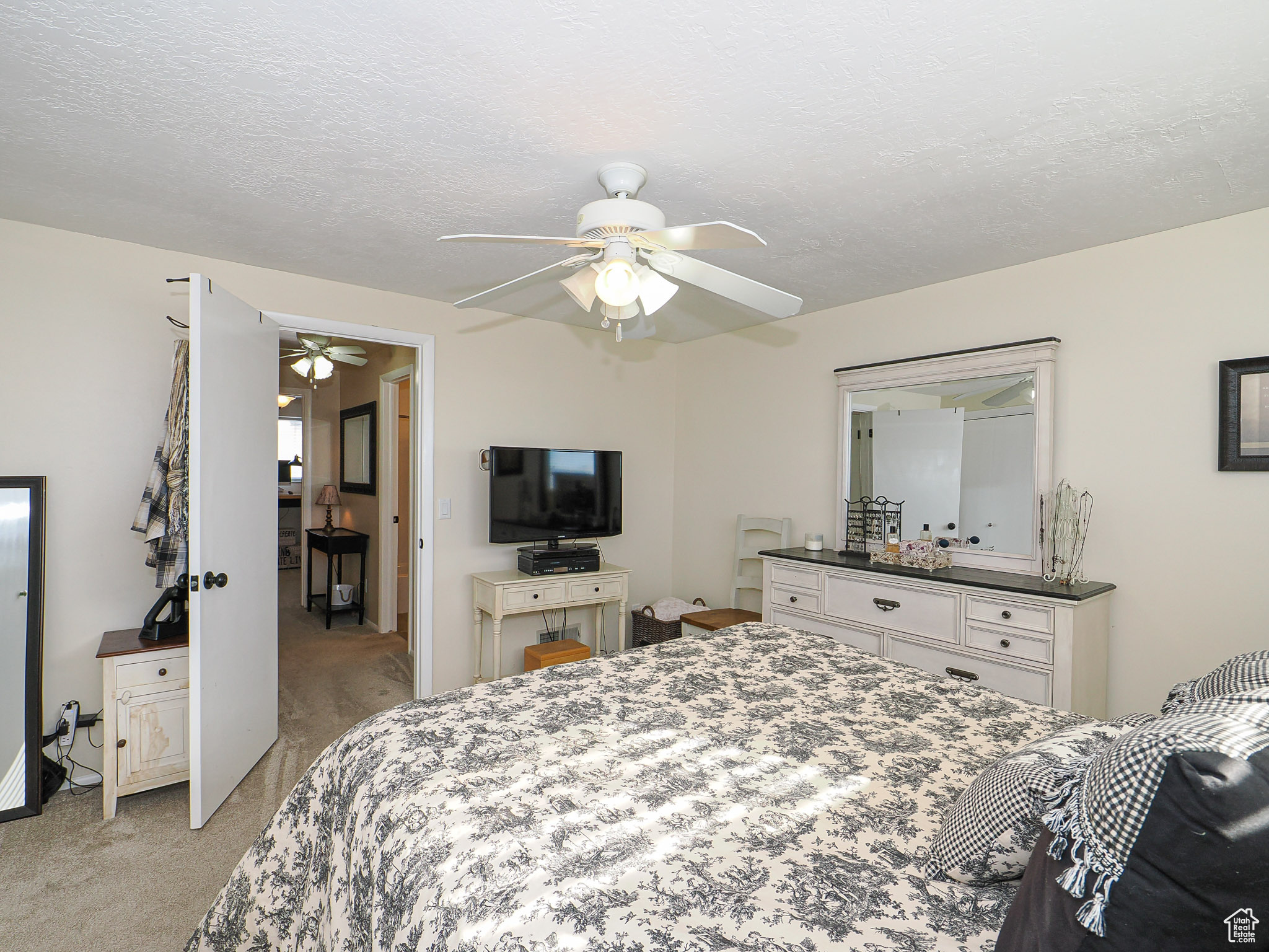 Bedroom featuring ceiling fan, light carpet, and a textured ceiling