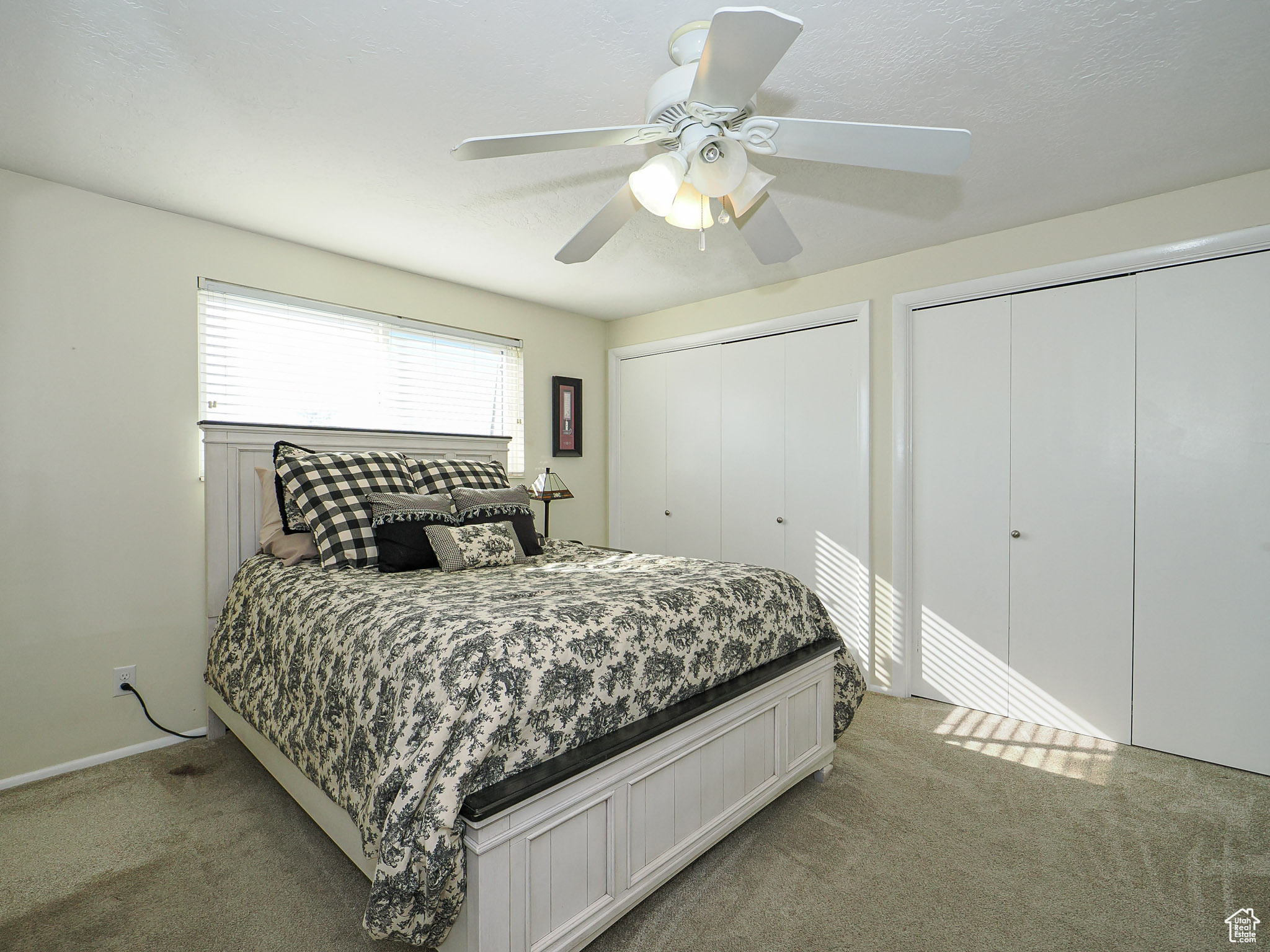 Bedroom with multiple closets, ceiling fan, and light carpet