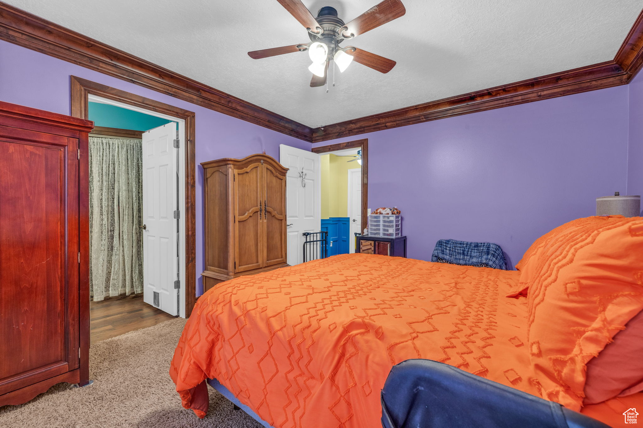 Bedroom with crown molding, light colored carpet, ceiling fan, and a textured ceiling