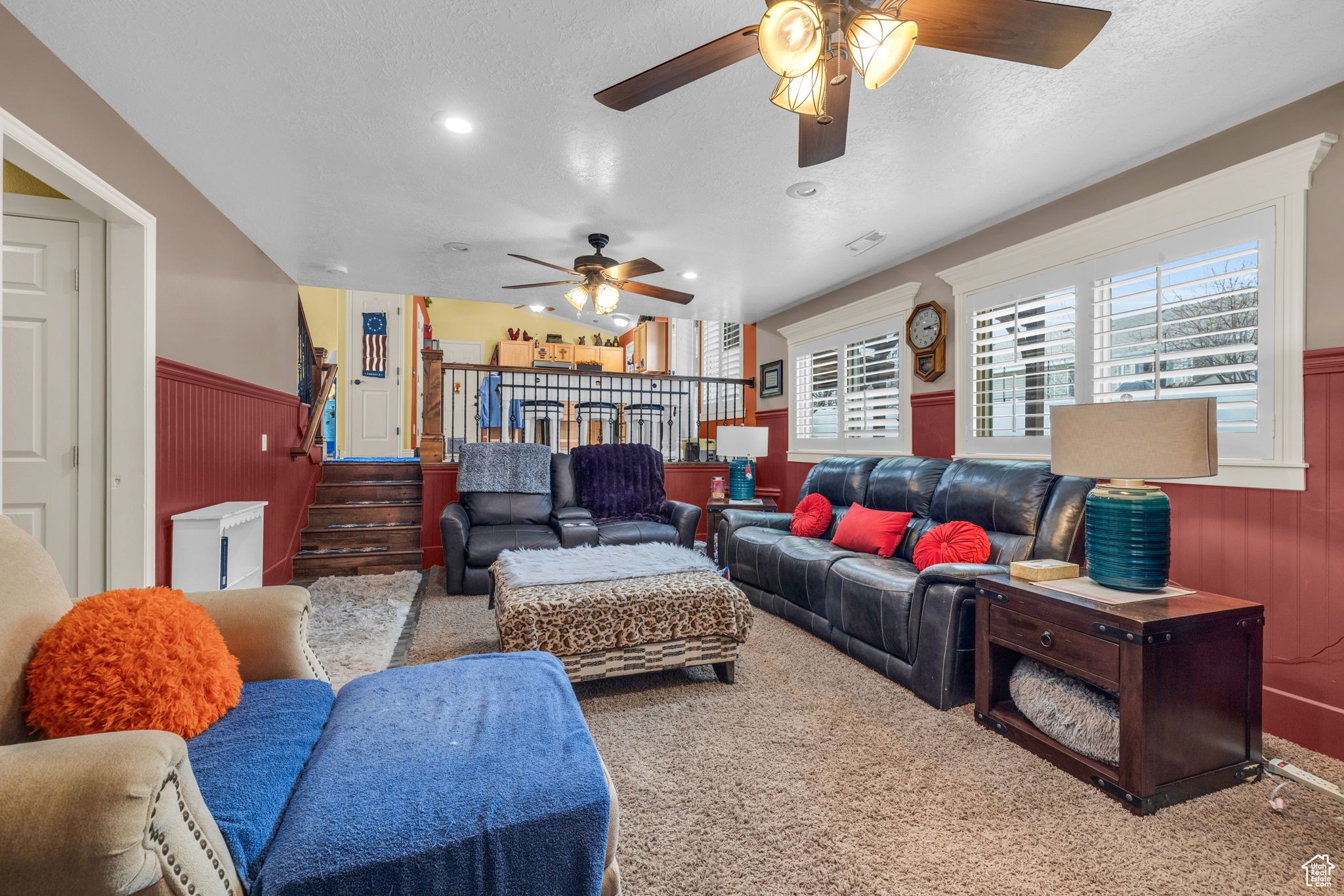 Living room with ceiling fan, carpet, a textured ceiling, and wood walls