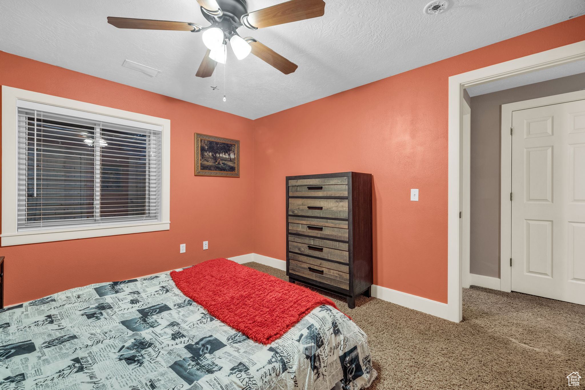 Bedroom with a textured ceiling, carpet floors, and ceiling fan