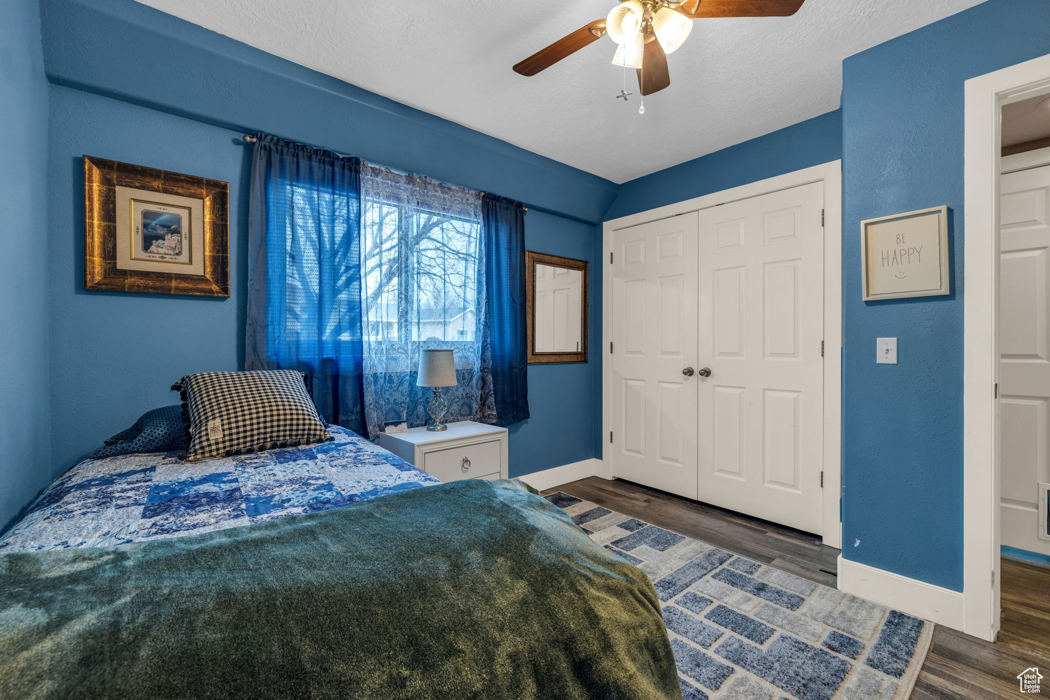 Bedroom with dark wood-type flooring, ceiling fan, and a closet