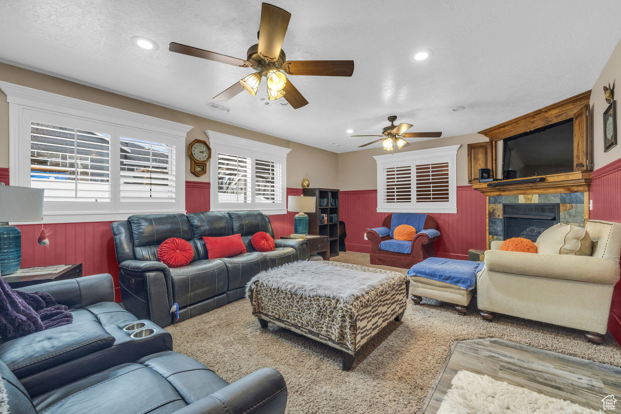 Living room with ceiling fan, wooden walls, a tile fireplace, and a textured ceiling