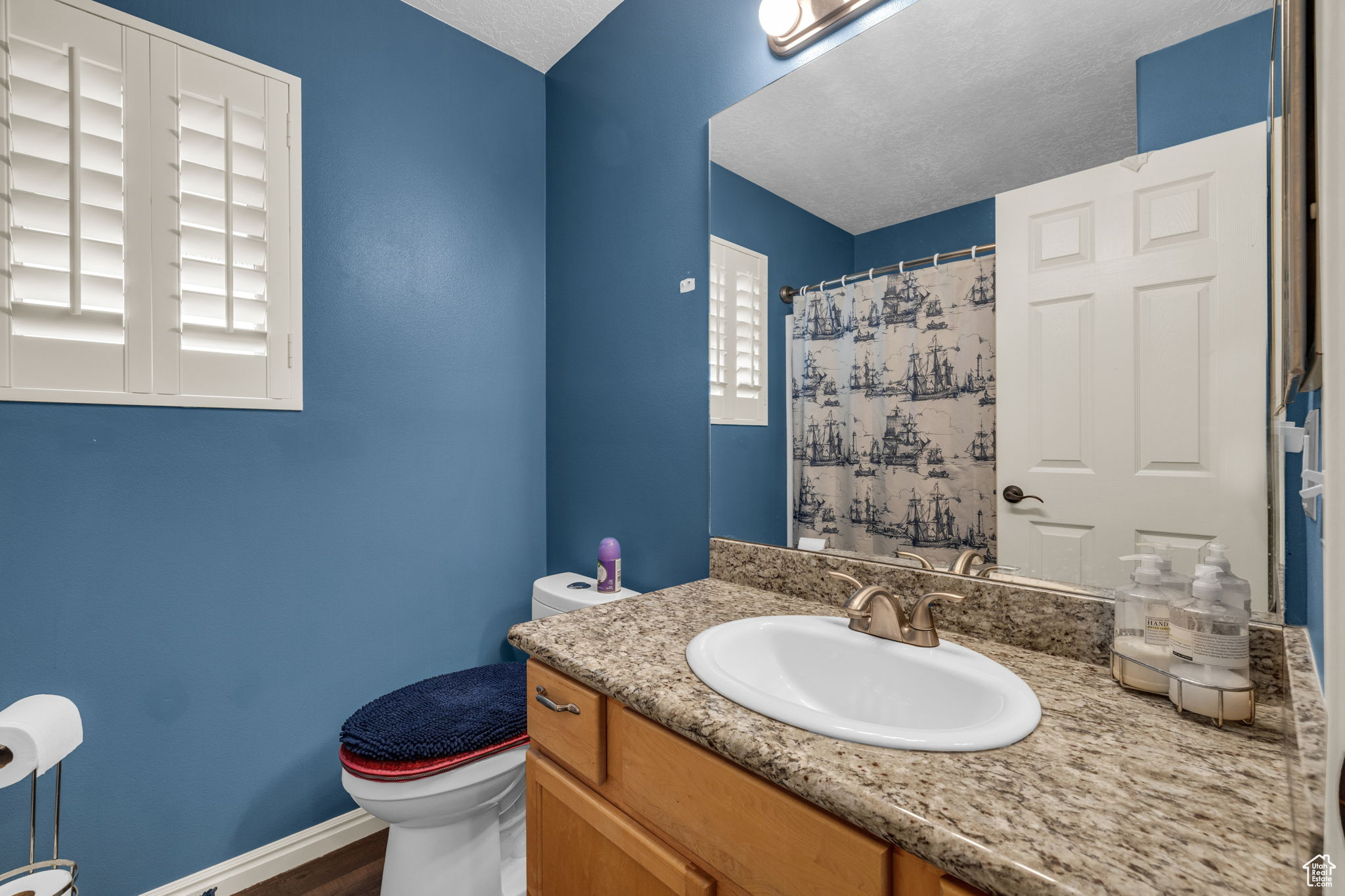 Bathroom with vanity, a textured ceiling, and toilet