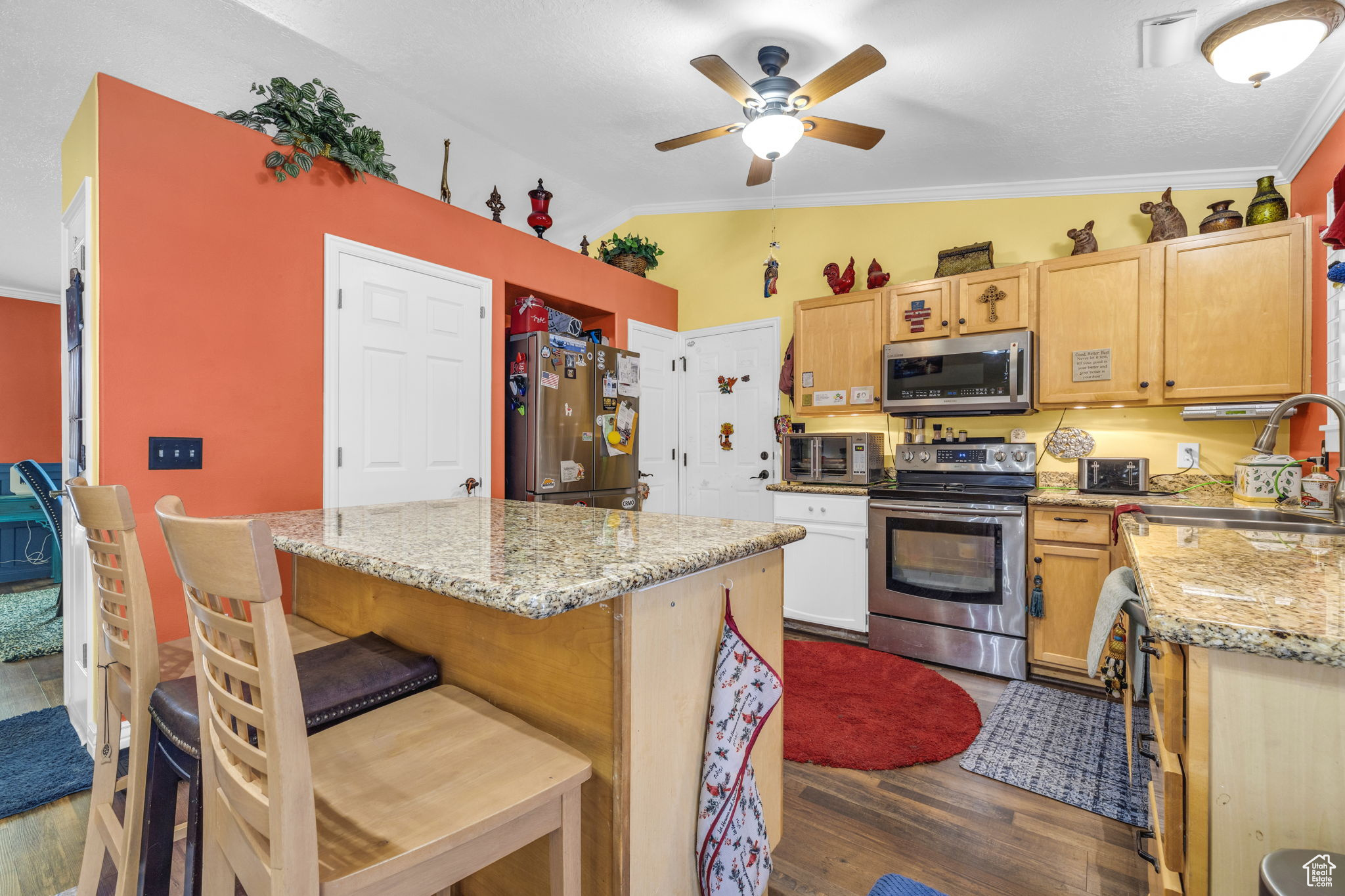 Kitchen with sink, appliances with stainless steel finishes, light stone countertops, dark hardwood / wood-style flooring, and vaulted ceiling