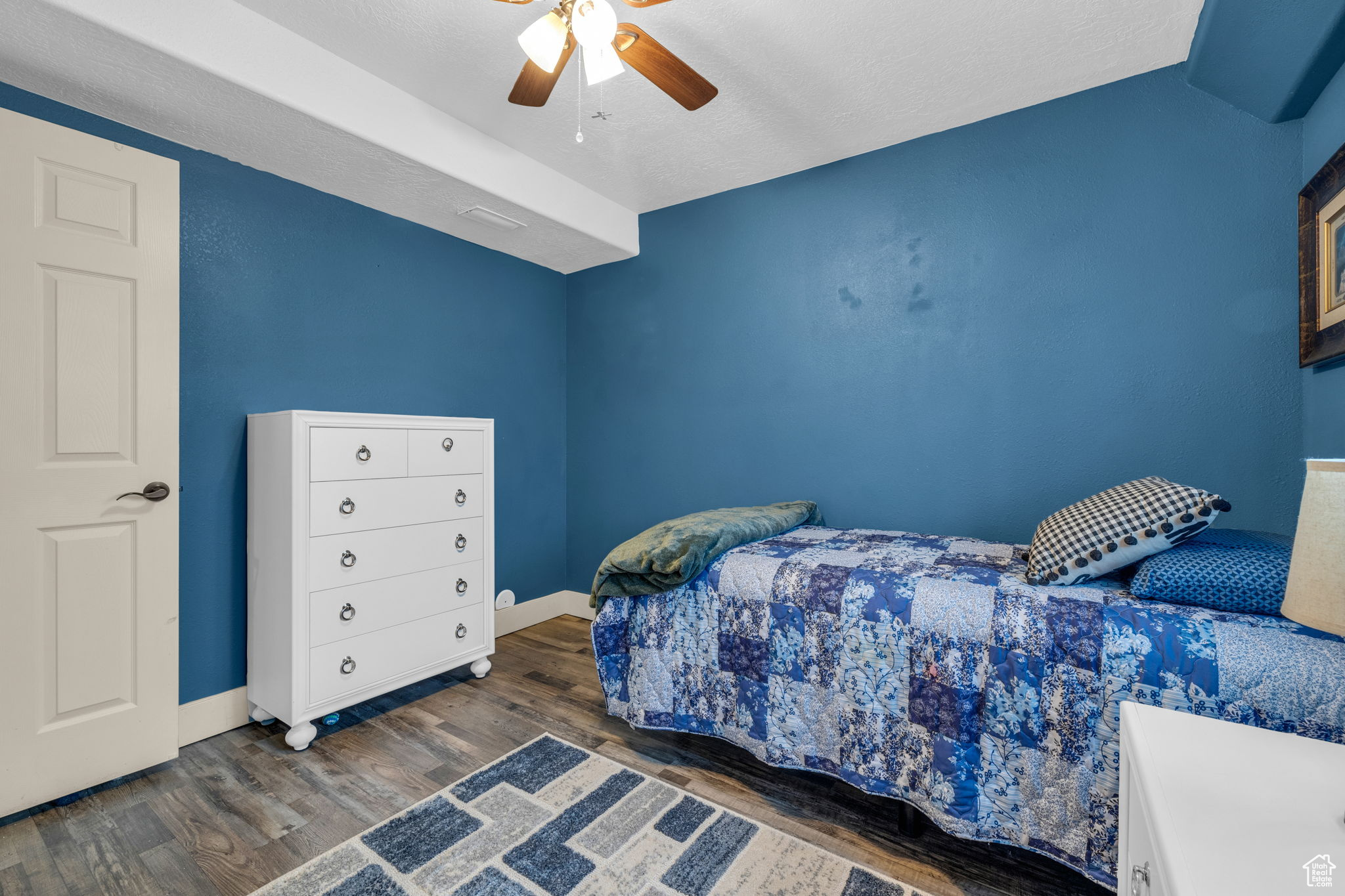 Bedroom featuring dark hardwood / wood-style flooring, a textured ceiling, and ceiling fan