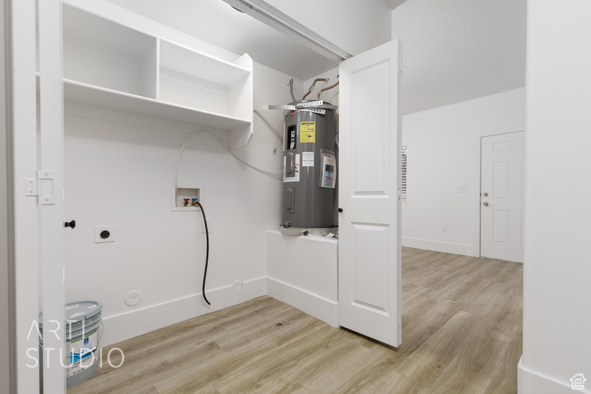 Laundry area with electric dryer hookup, electric water heater, washer hookup, and light wood-type flooring