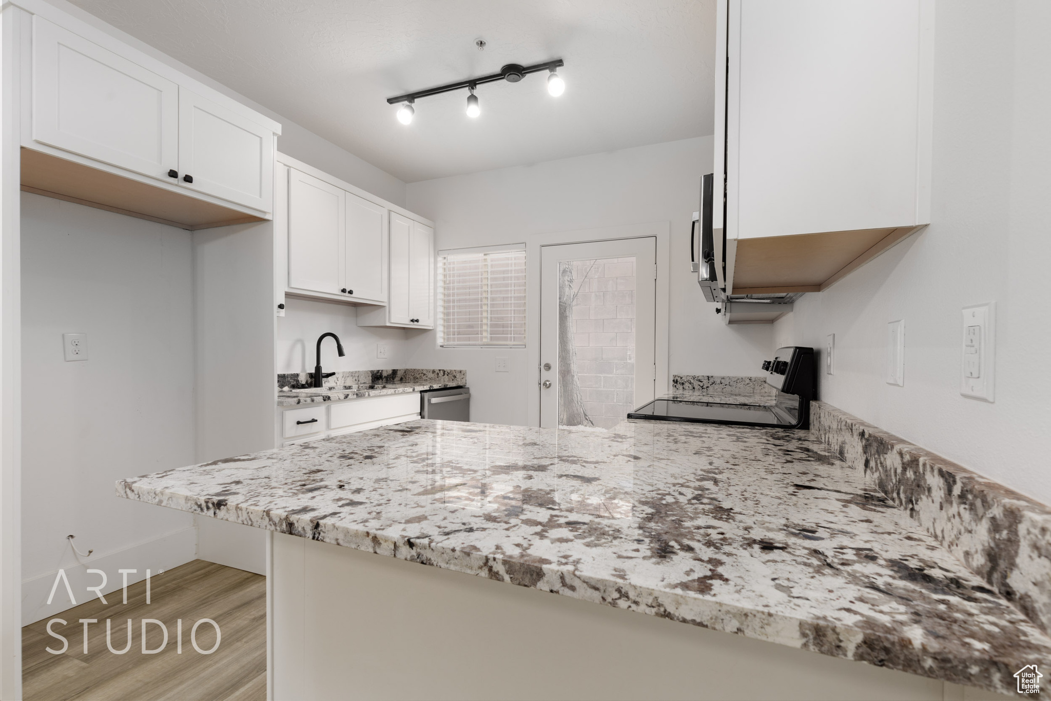 Kitchen featuring white cabinetry, sink, stainless steel appliances, light stone countertops, and light hardwood / wood-style flooring
