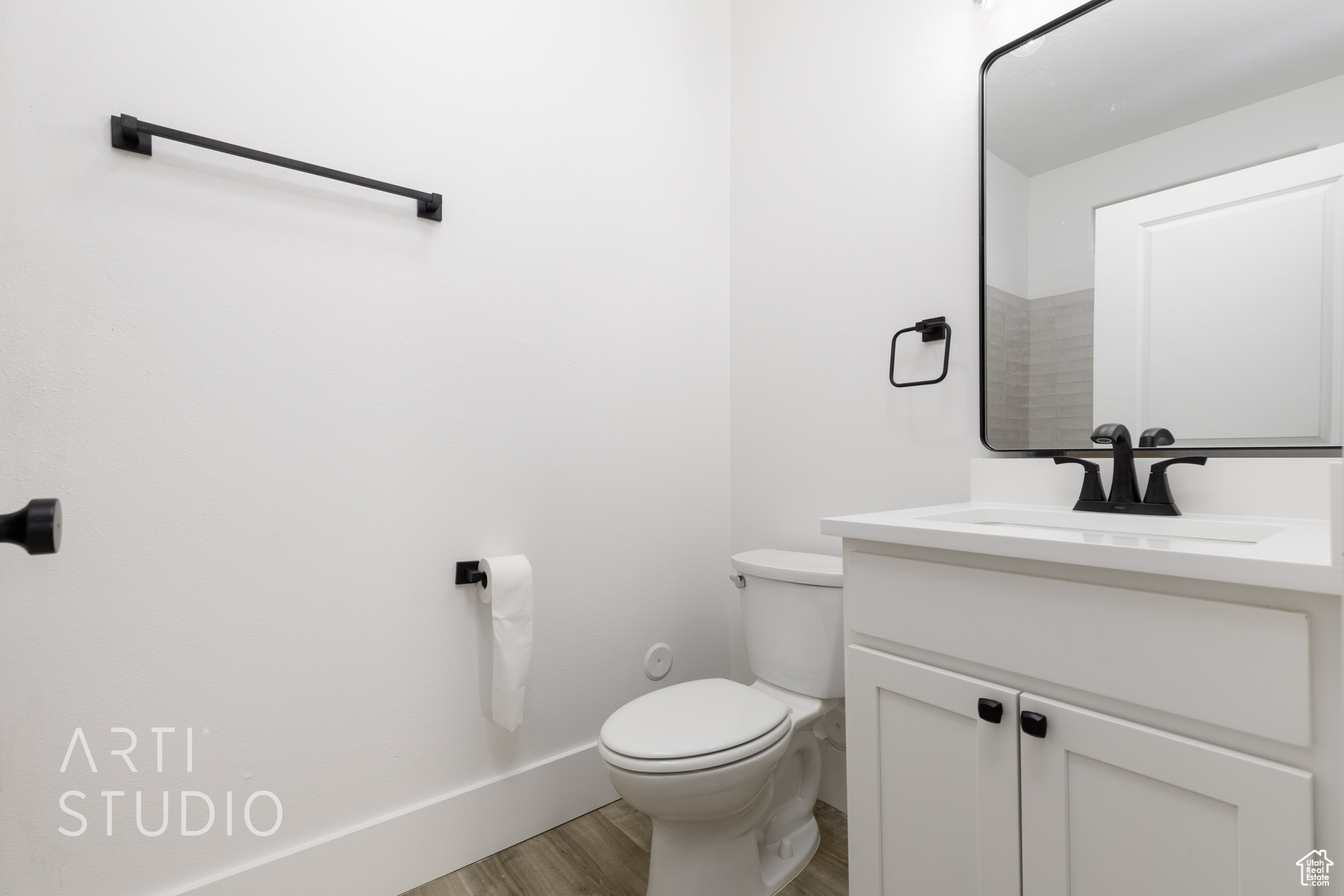 Bathroom with hardwood / wood-style flooring, vanity, and toilet