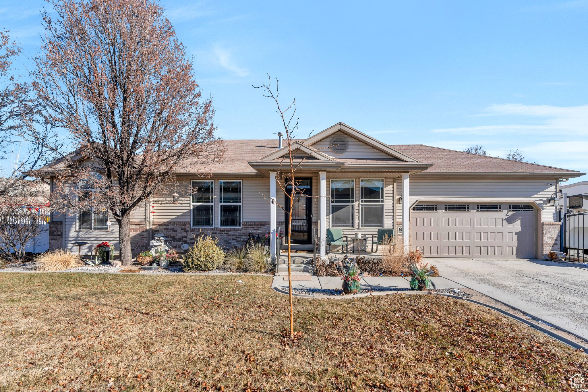 Single story home featuring a garage, a front yard, and covered porch