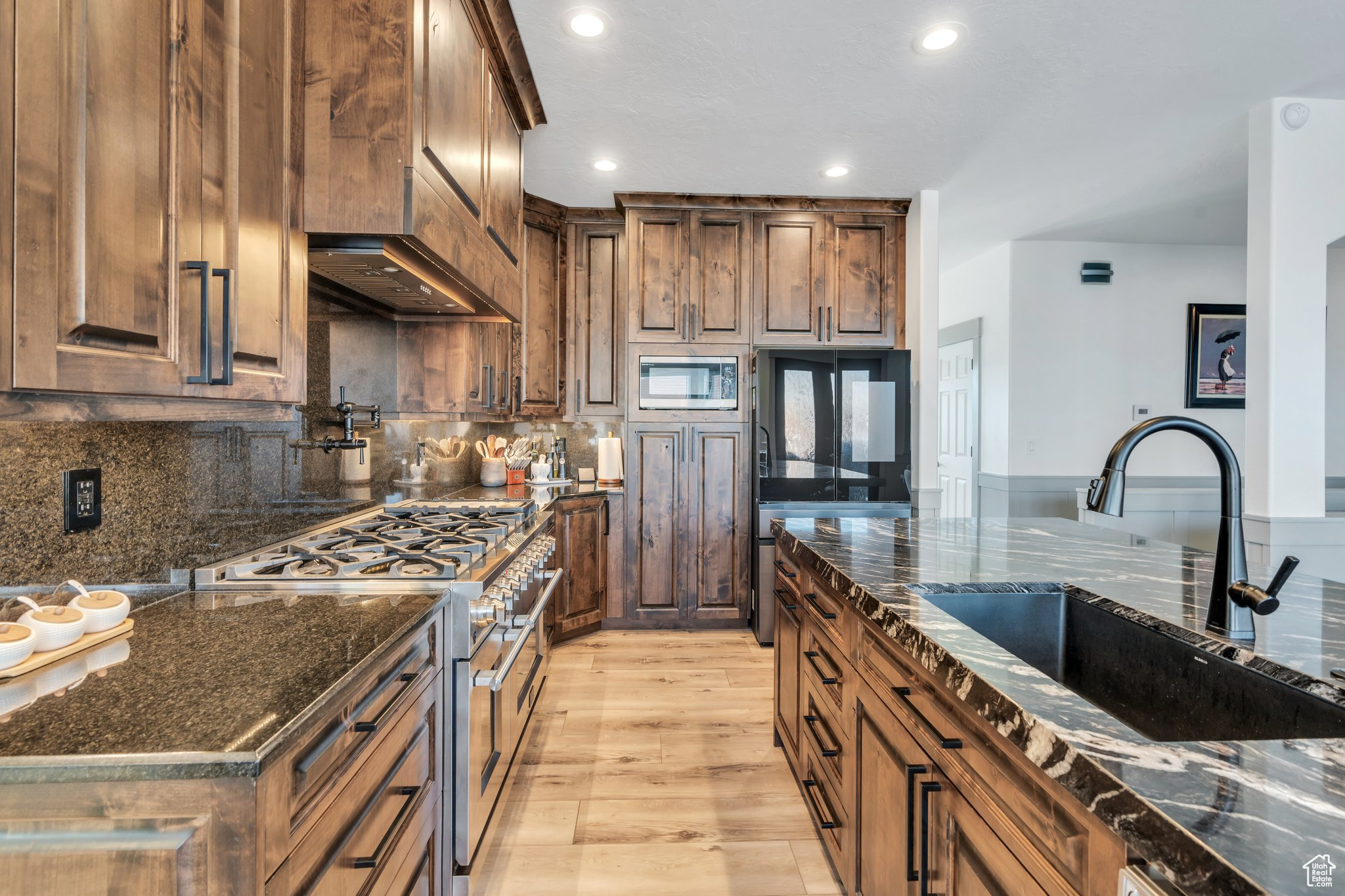 Kitchen with sink, backsplash, stainless steel appliances, and dark stone counters