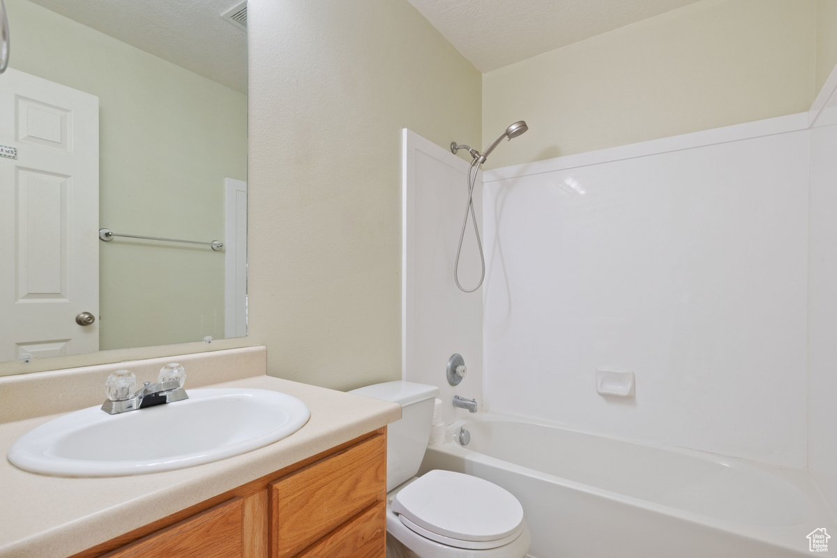 Full bathroom with bathtub / shower combination, vanity, and toilet