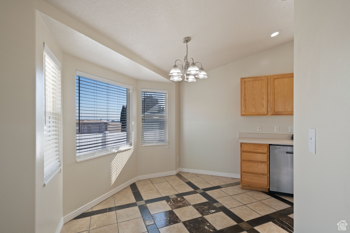 Kitchen featuring hanging light fixtures, dishwasher, lofted ceiling, and a wealth of natural light