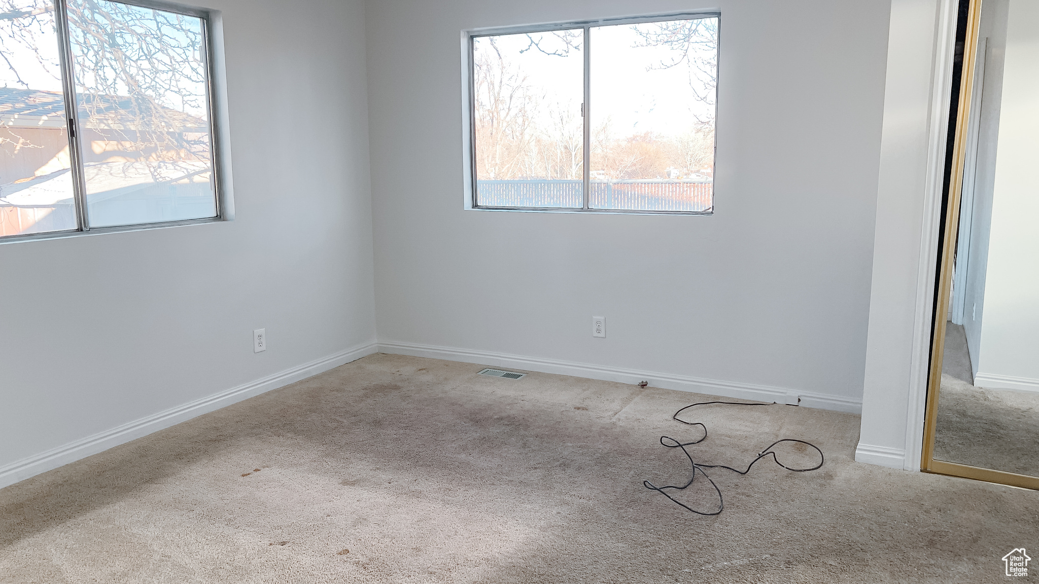 Empty room featuring a healthy amount of sunlight and light colored carpet