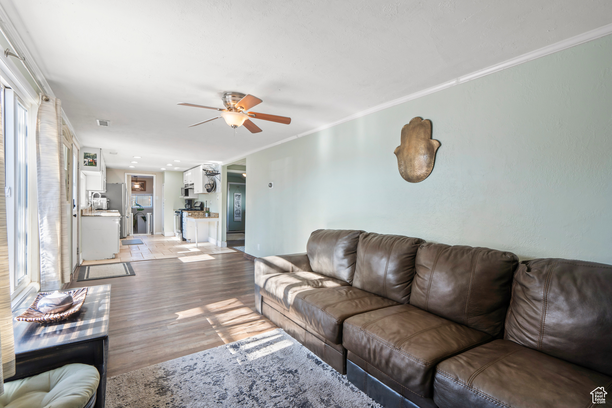 Living room featuring ceiling fan, ornamental molding, and light hardwood / wood-style floors