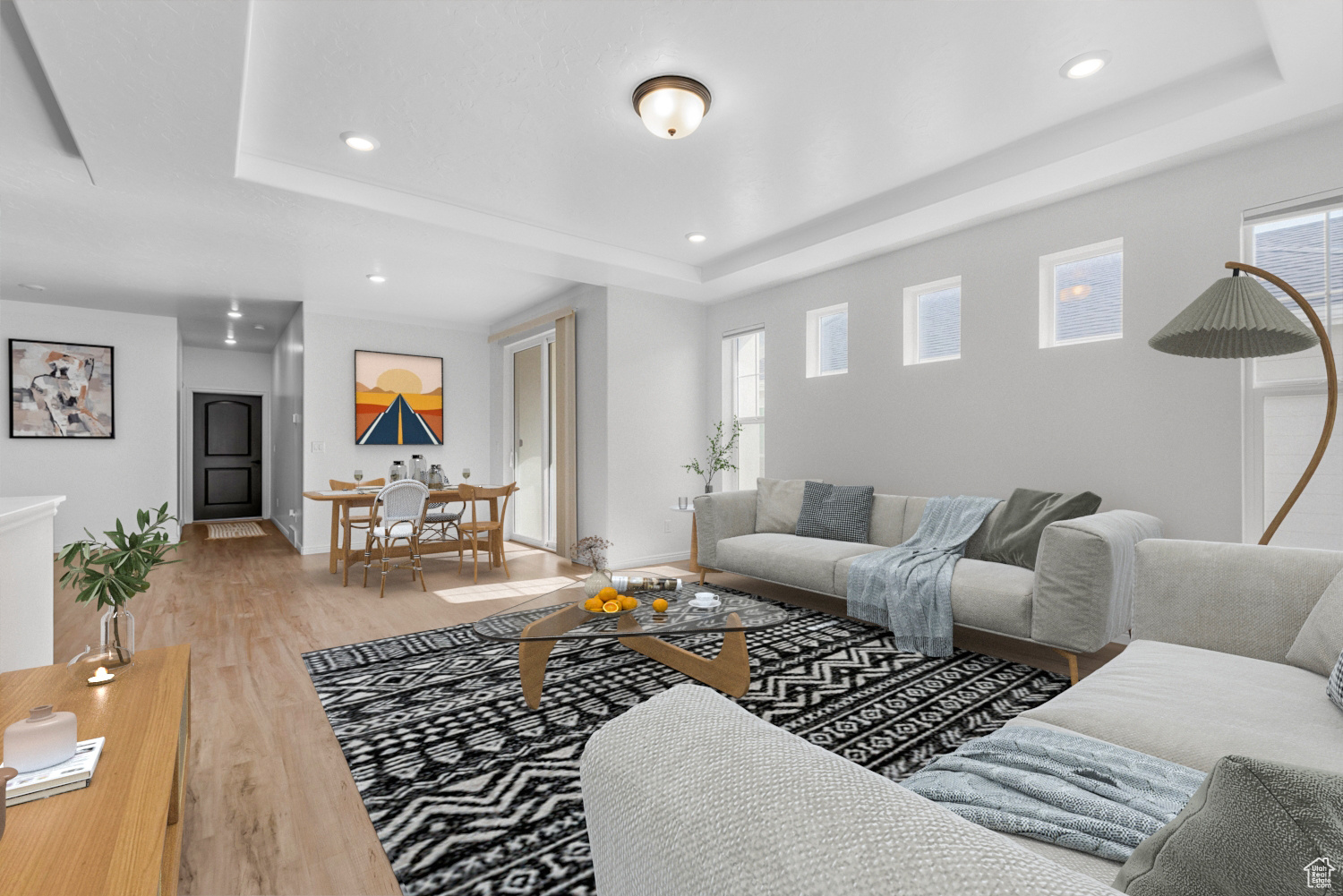 Living room with a raised ceiling, a healthy amount of sunlight, and light wood-type flooring