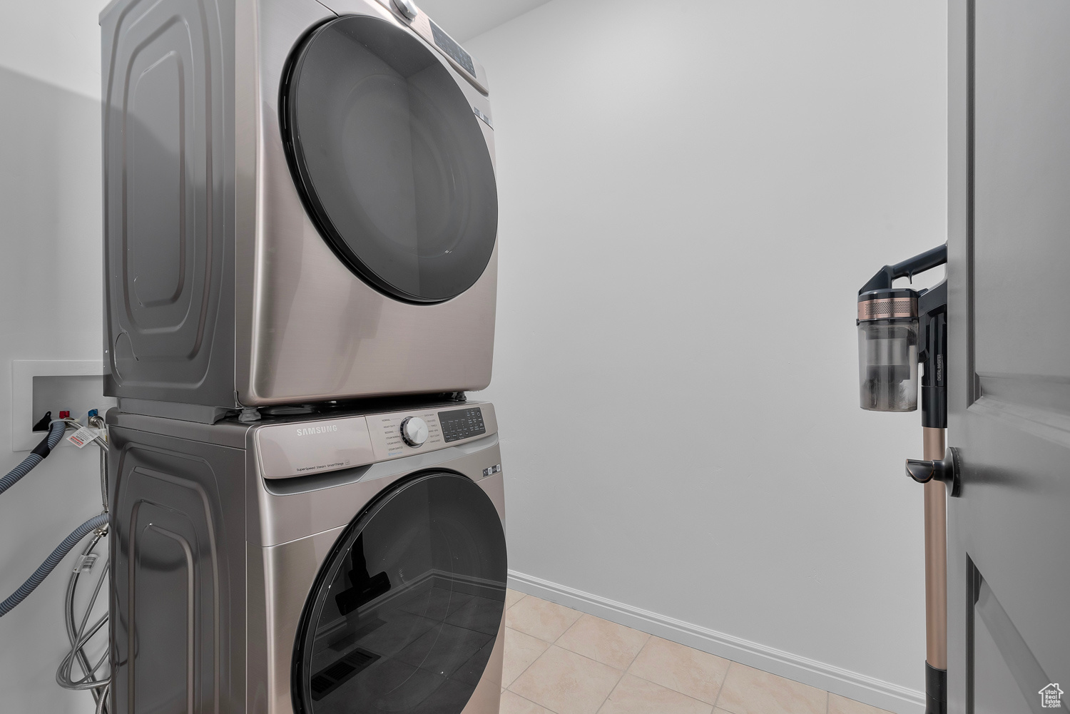 Laundry room featuring light tile patterned floors and stacked washing maching and dryer