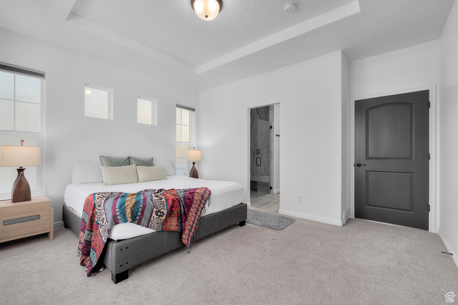 Bedroom featuring ensuite bath, a tray ceiling, and carpet floors