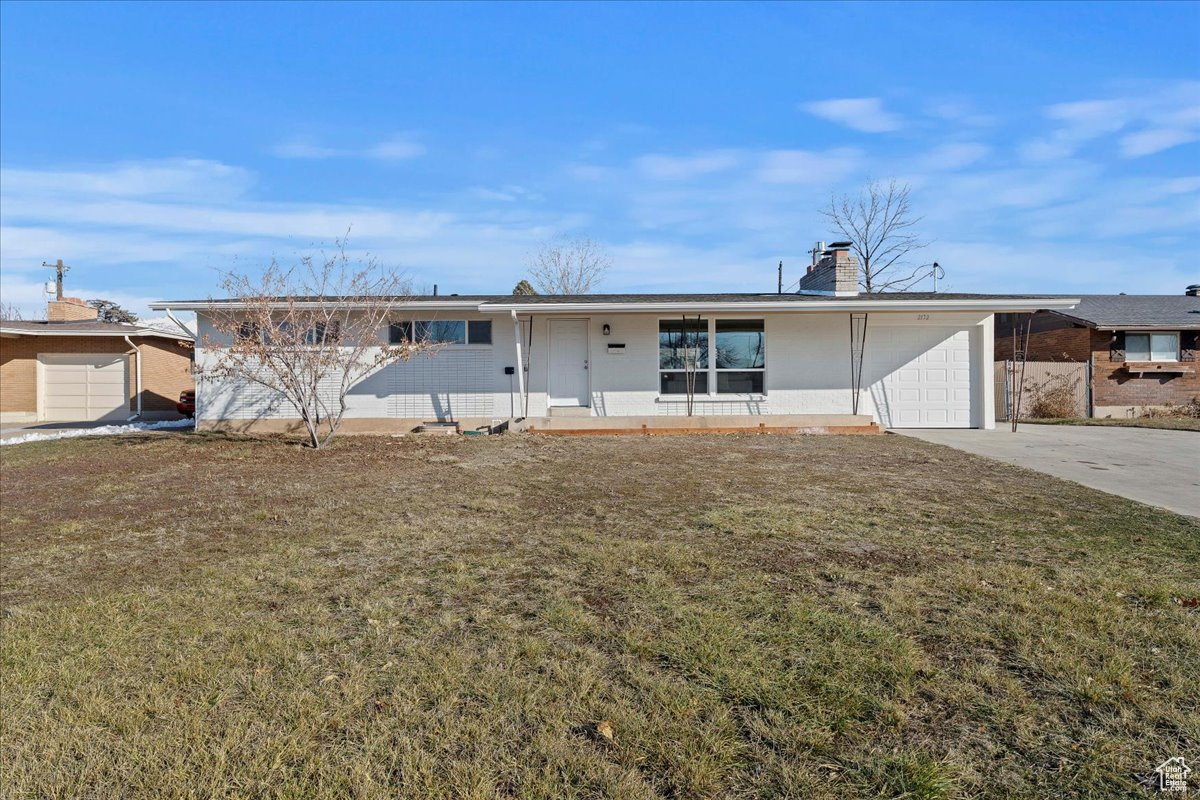 Ranch-style home with a garage, a front lawn, a carport, and a porch