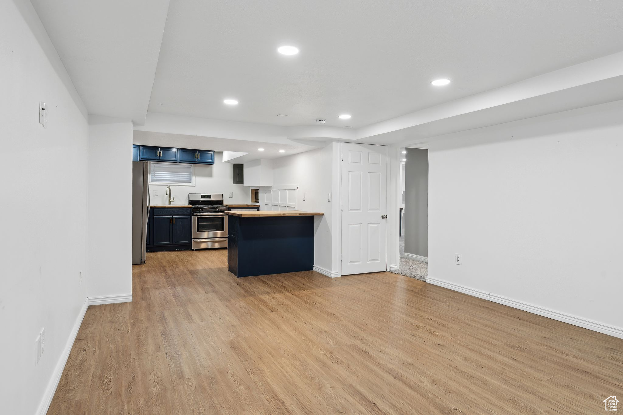 Kitchen featuring butcher block counters, sink, a kitchen bar, stainless steel appliances, and light hardwood / wood-style flooring