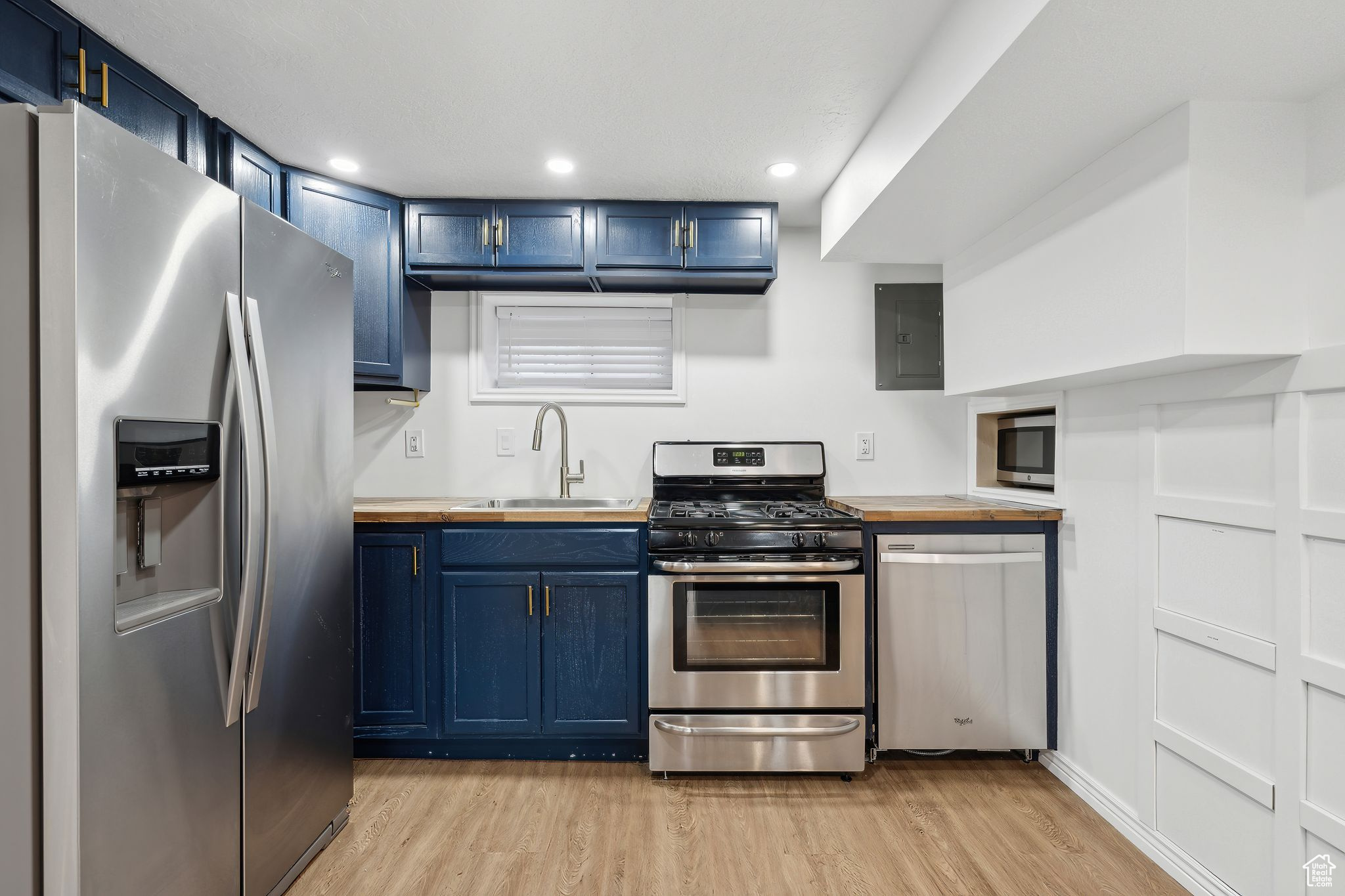 Kitchen with wood counters, sink, stainless steel appliances, and blue cabinets