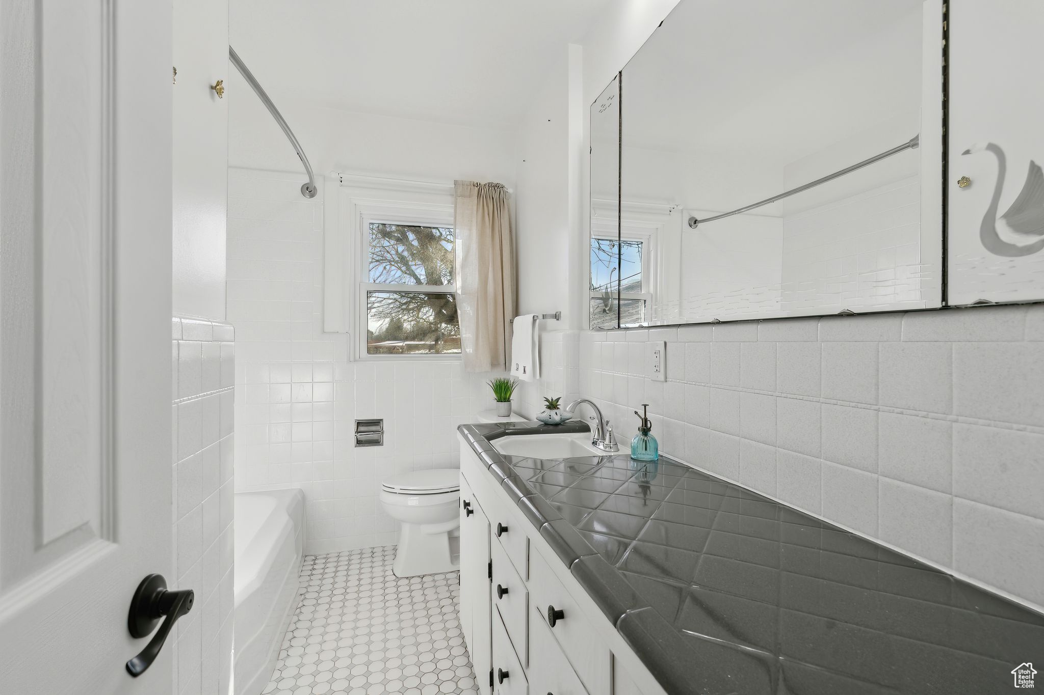 Full bathroom with shower / bathing tub combination, tile walls, tile patterned flooring, vanity, and toilet