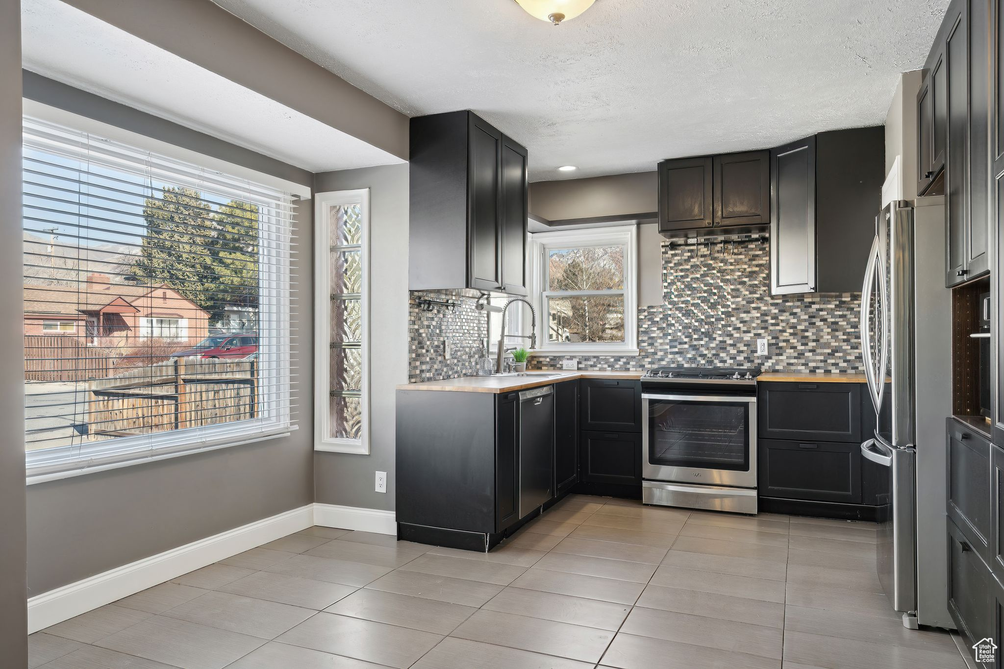 Kitchen featuring backsplash, light tile patterned floors, sink, and appliances with stainless steel finishes