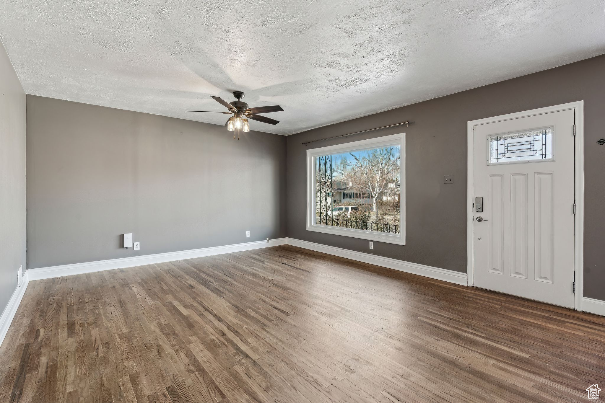 Entryway with wood-type flooring, ceiling fan, and a textured ceiling