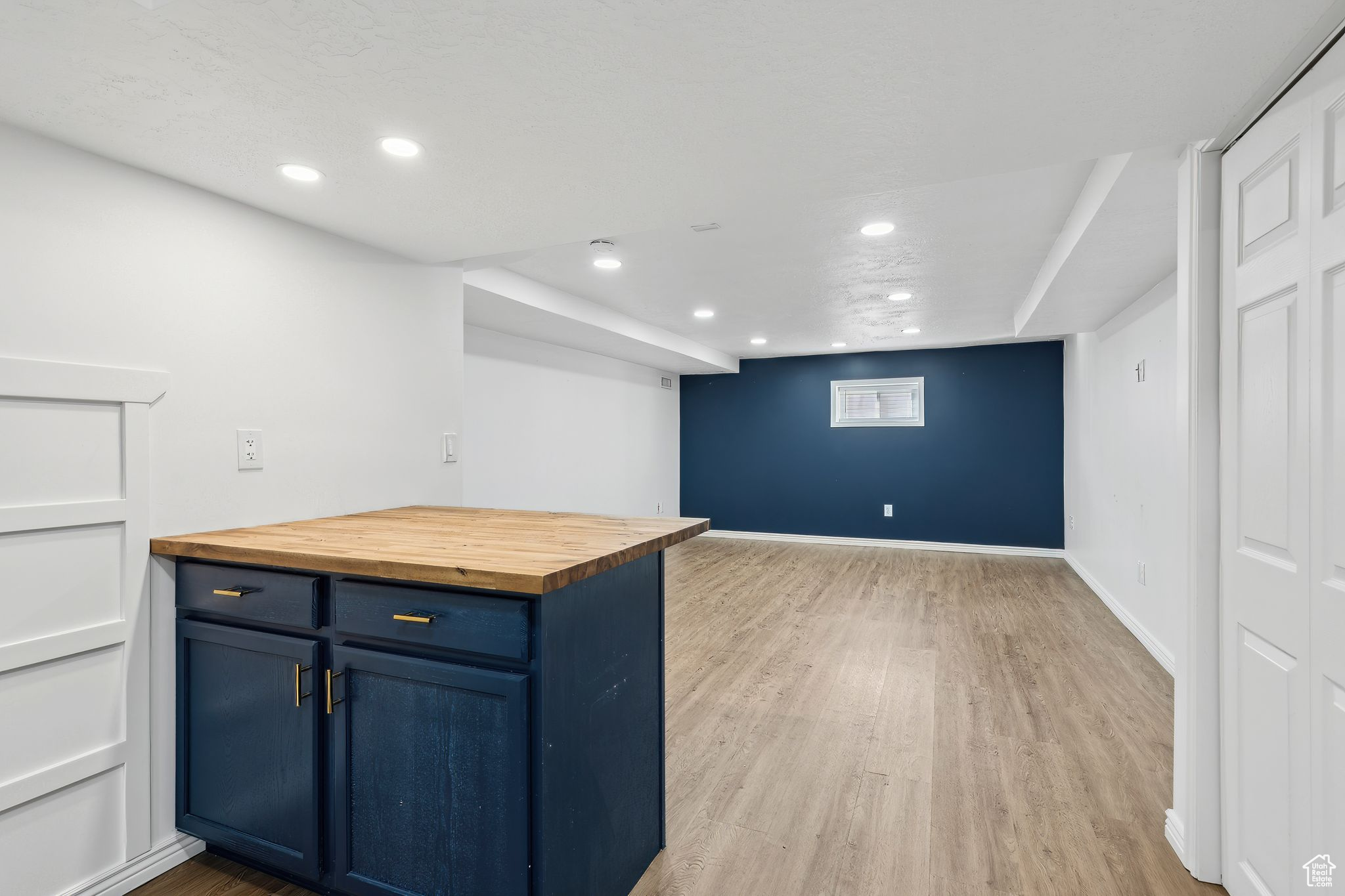 Kitchen with blue cabinetry, butcher block countertops, and light hardwood / wood-style floors