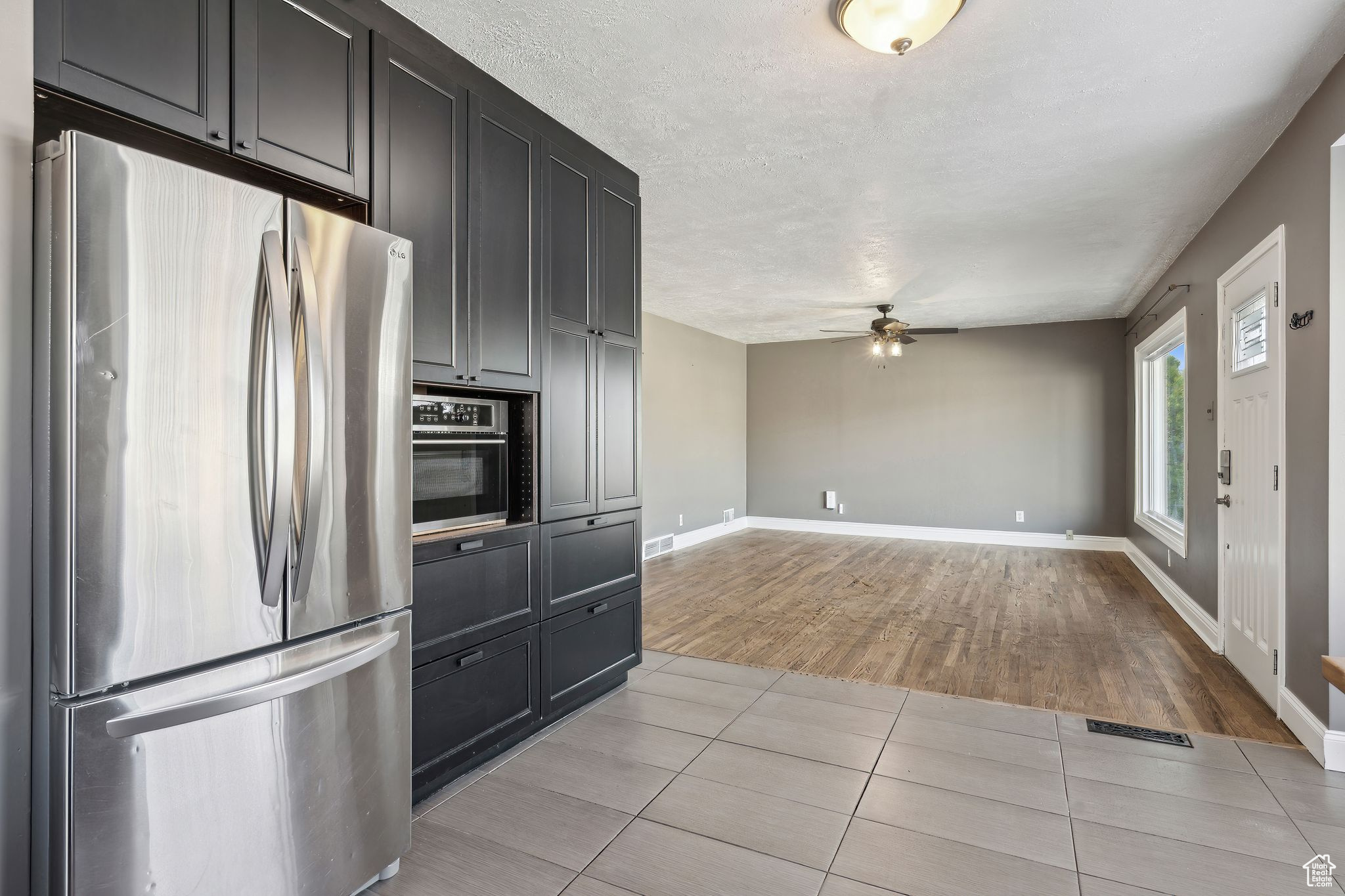 Kitchen with light tile patterned floors, a textured ceiling, stainless steel fridge, and ceiling fan