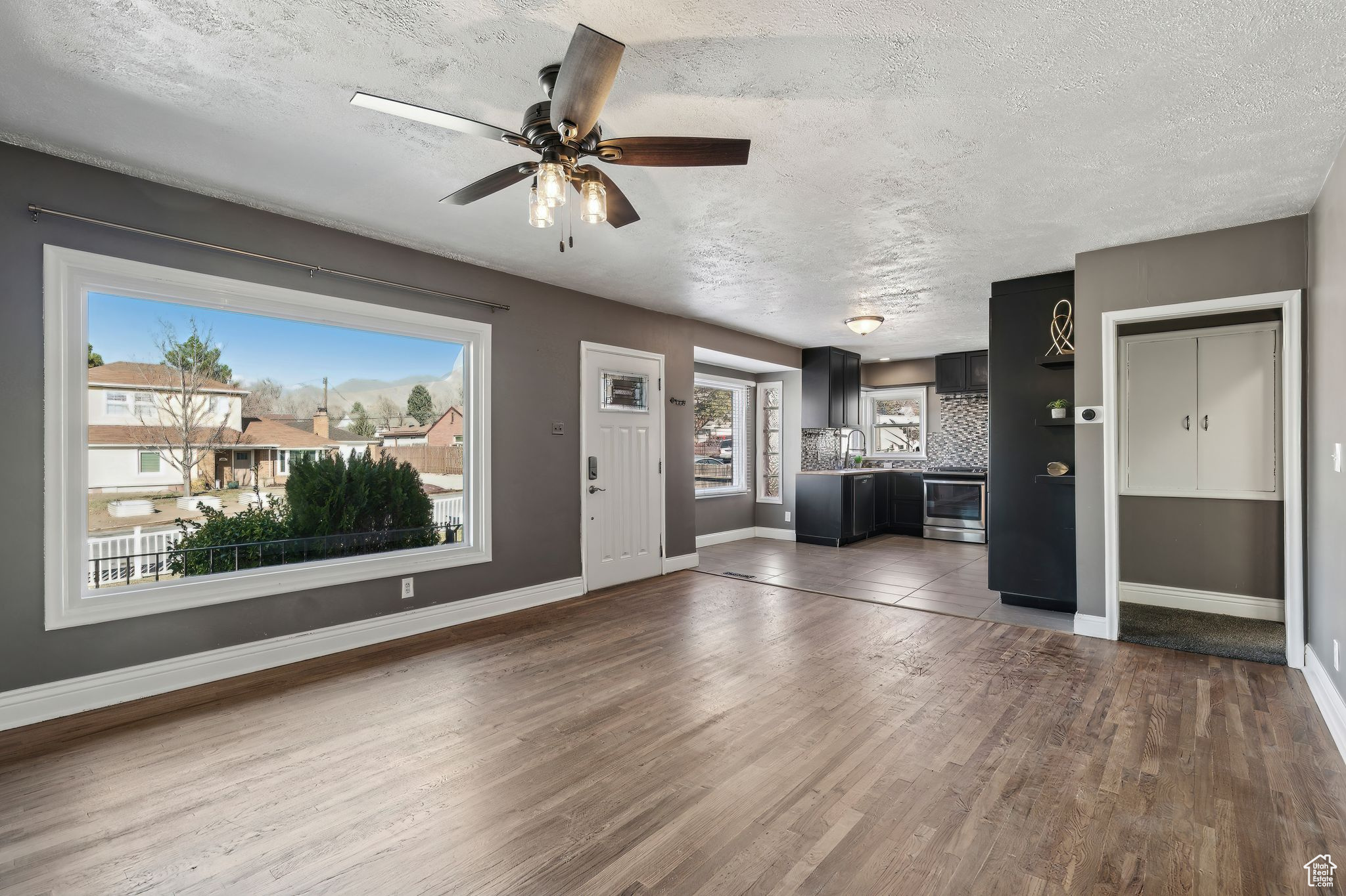 Unfurnished living room featuring ceiling fan, a textured ceiling, and dark hardwood / wood-style flooring