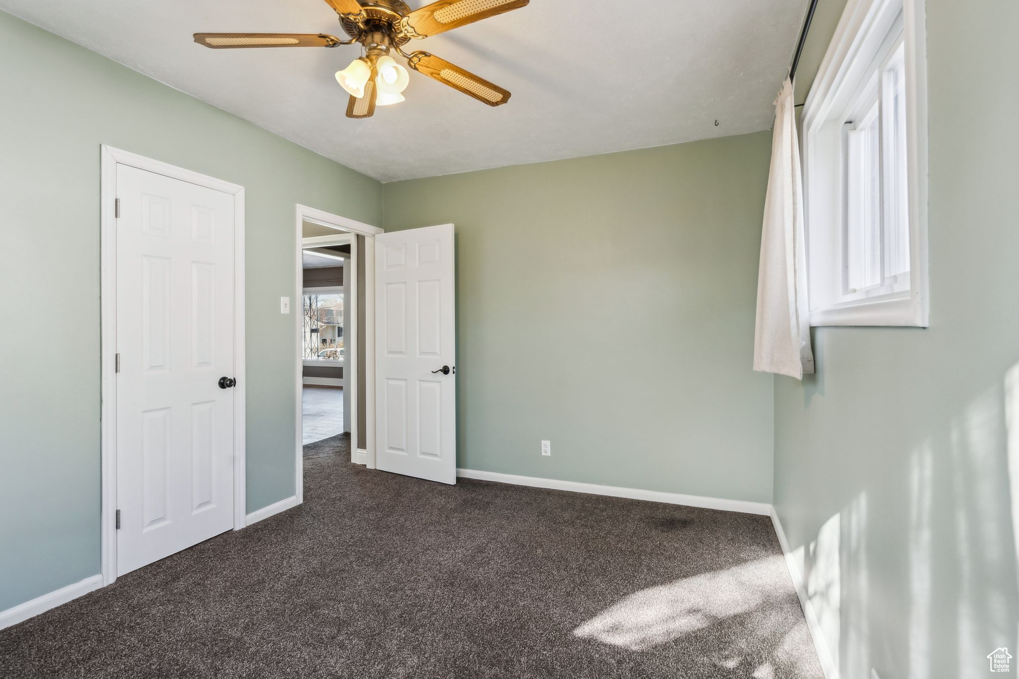 Carpeted empty room featuring ceiling fan