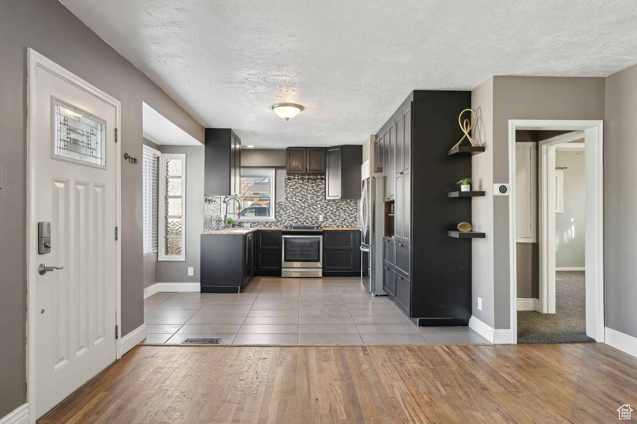 Kitchen featuring stainless steel appliances, light hardwood / wood-style floors, a textured ceiling, and backsplash