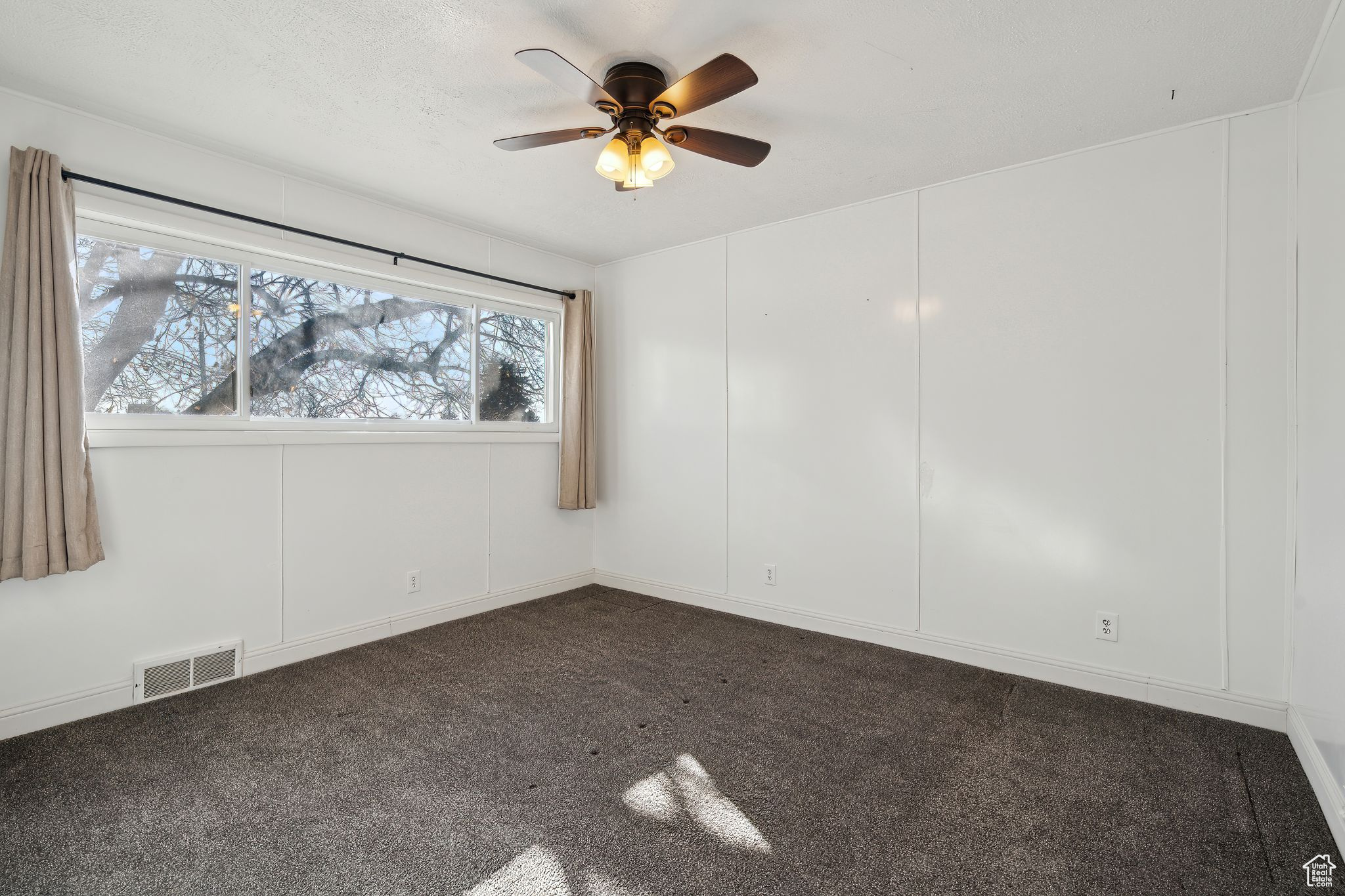 Carpeted empty room featuring ceiling fan