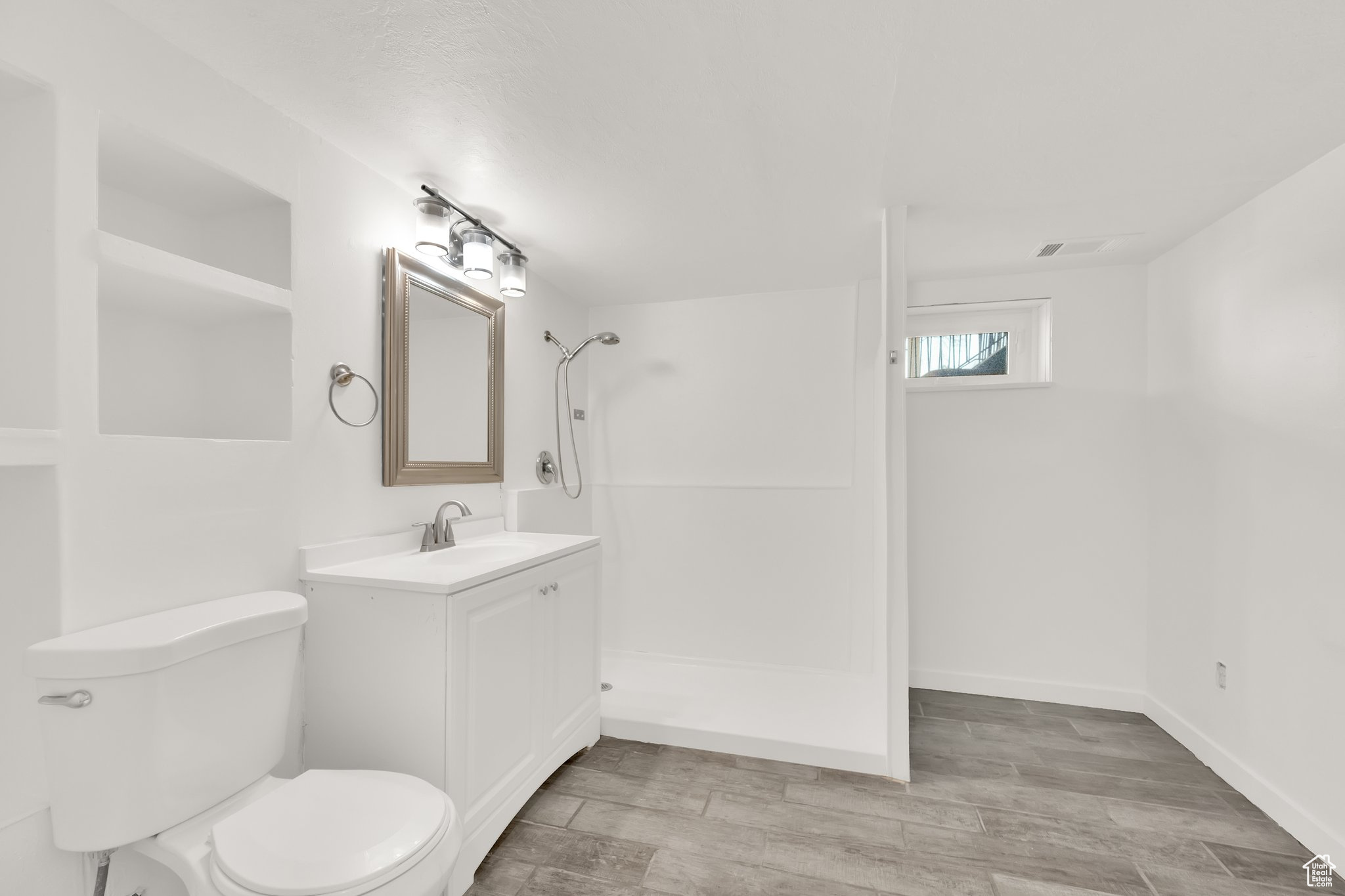 Bathroom featuring vanity, toilet, and walk in shower