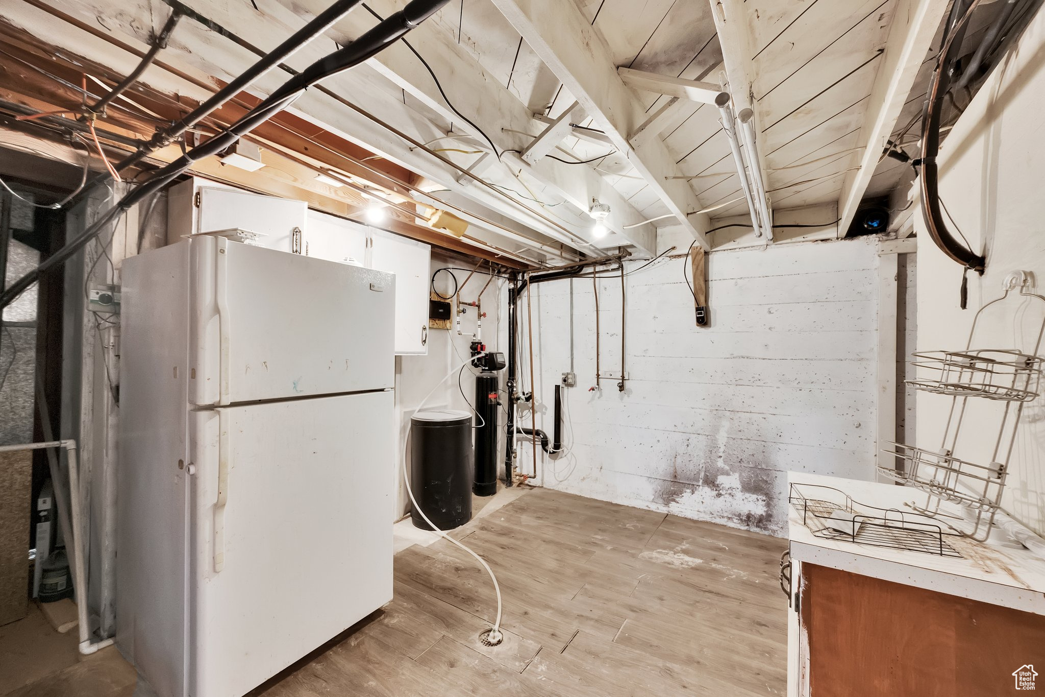 Basement featuring light wood-type flooring and white fridge