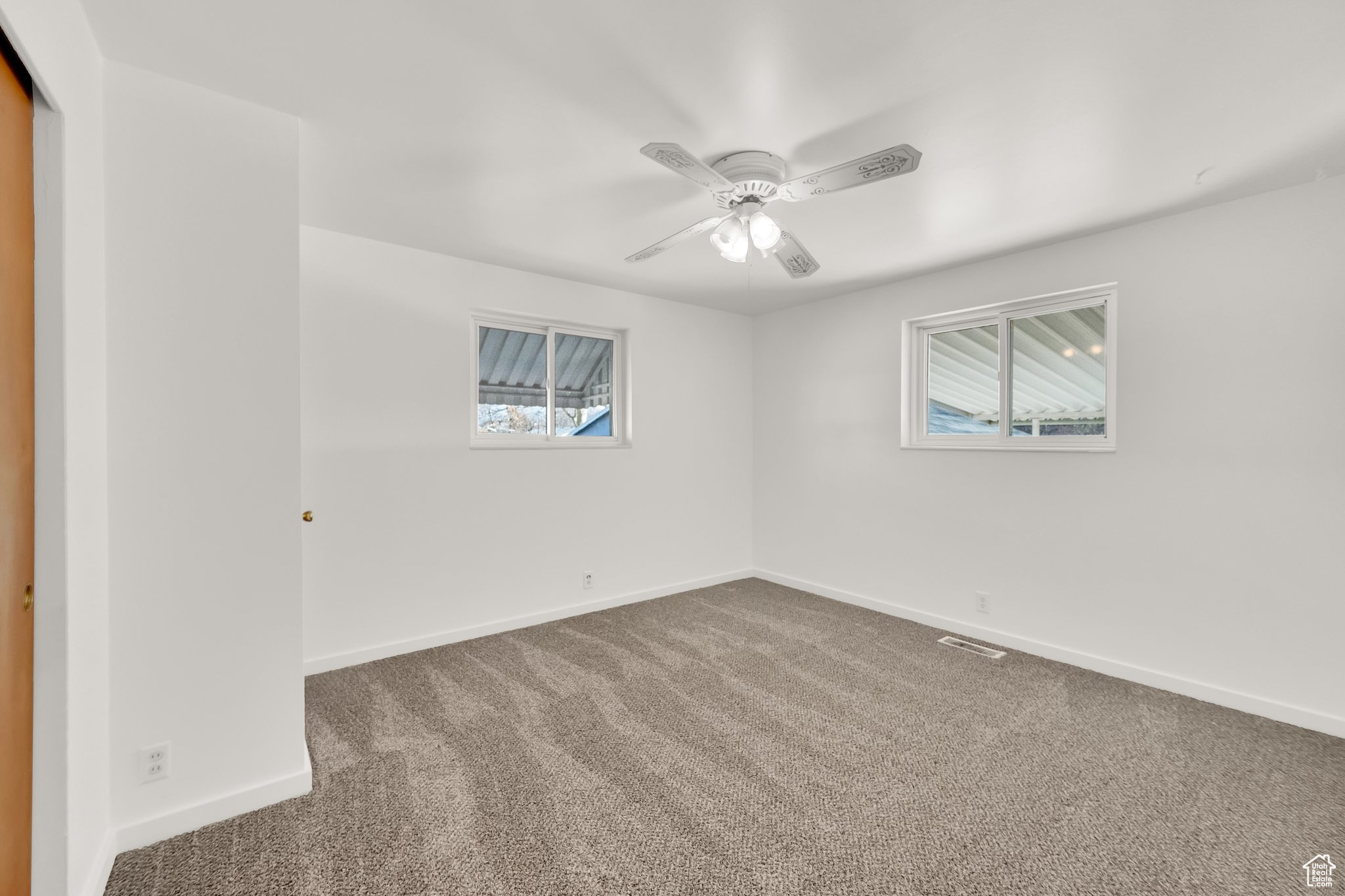 Carpeted spare room featuring ceiling fan