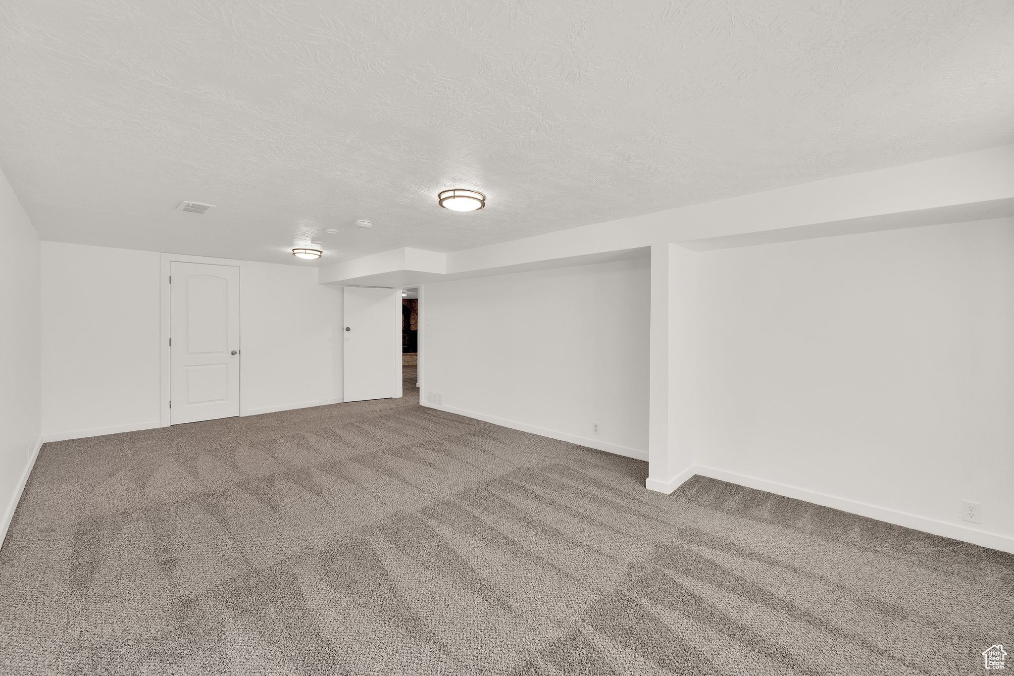 Carpeted spare room featuring a textured ceiling