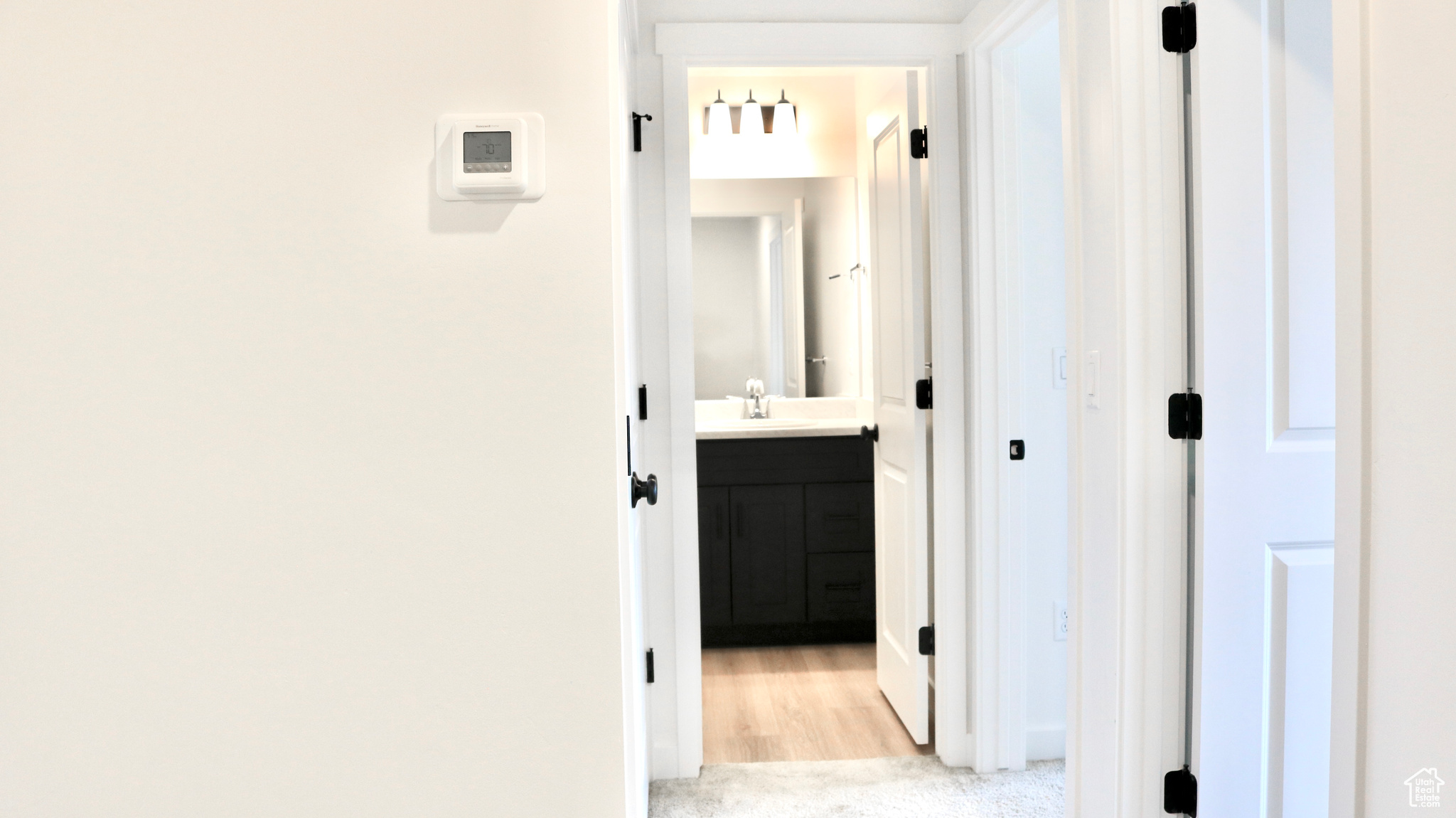 Corridor featuring sink and light carpet