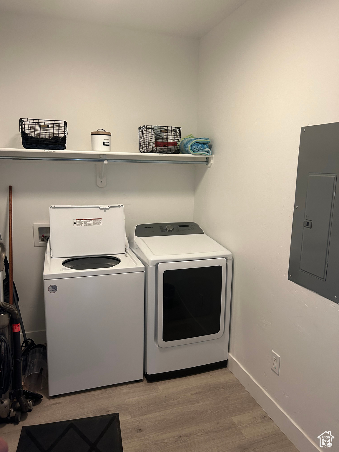 Laundry room with washing machine and clothes dryer, electric panel, and light hardwood / wood-style floors