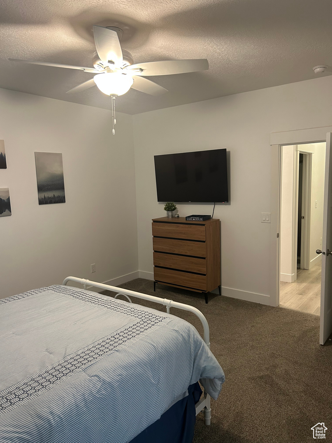 Carpeted bedroom with ceiling fan and a textured ceiling