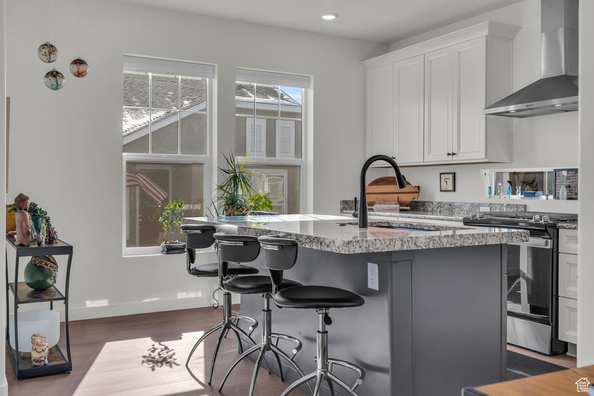 Kitchen with a center island with  double sinks, stainless steel range oven, a breakfast bar area, and wall chimney range hood