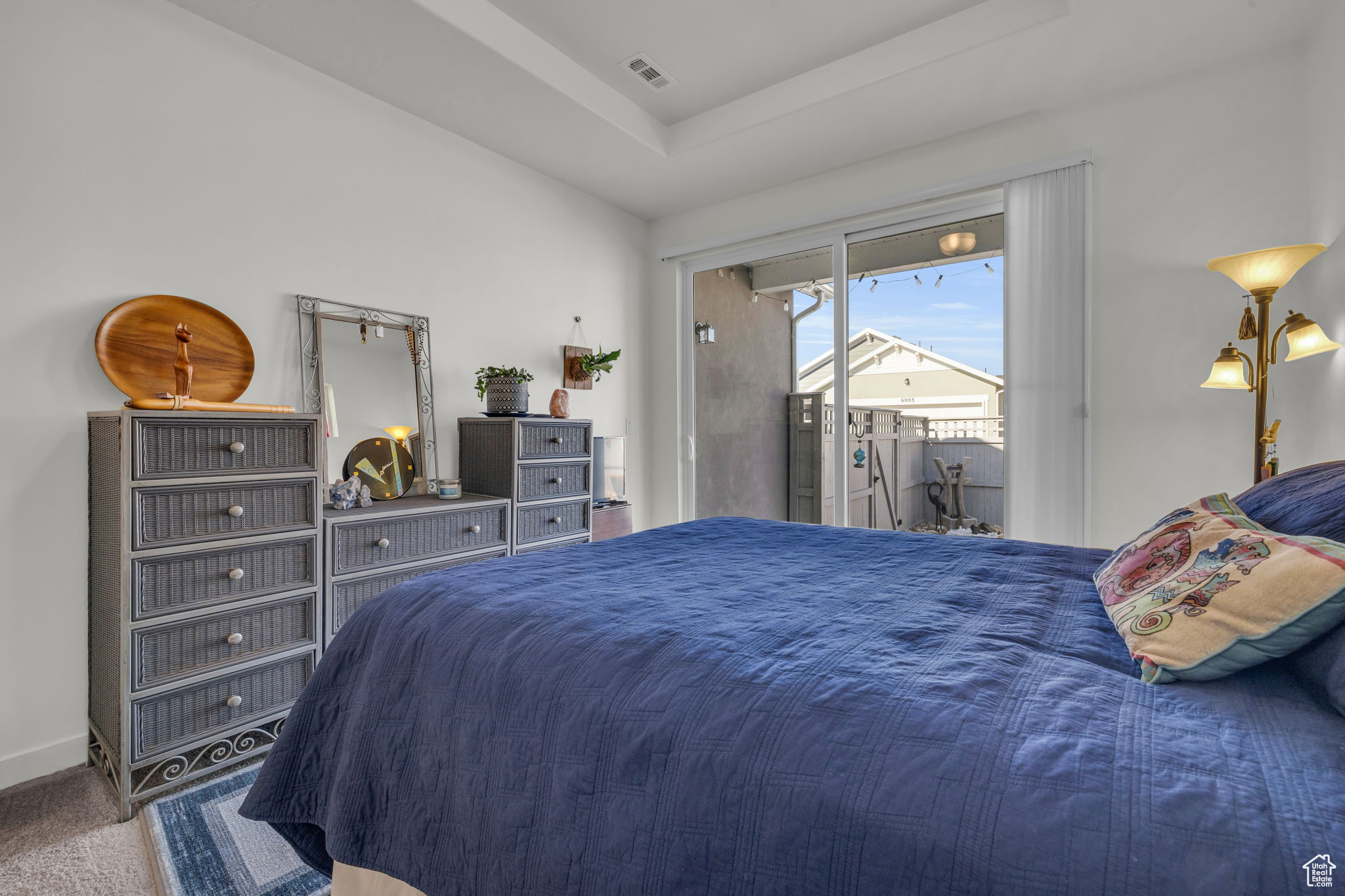 Primary Bedroom with a raised ceiling, carpet floors, and private patio.