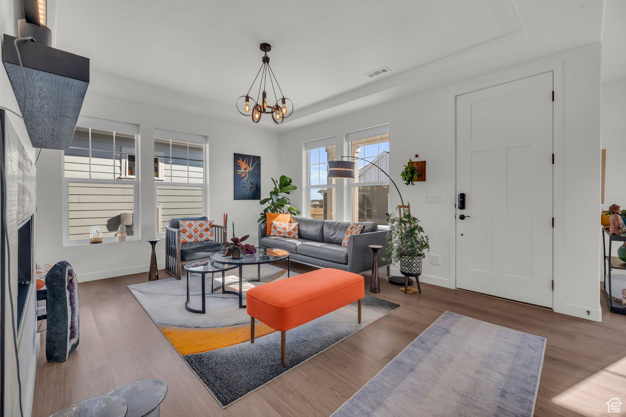 Living room with an inviting chandelier, dark hardwood / wood-style floors, and a raised ceiling