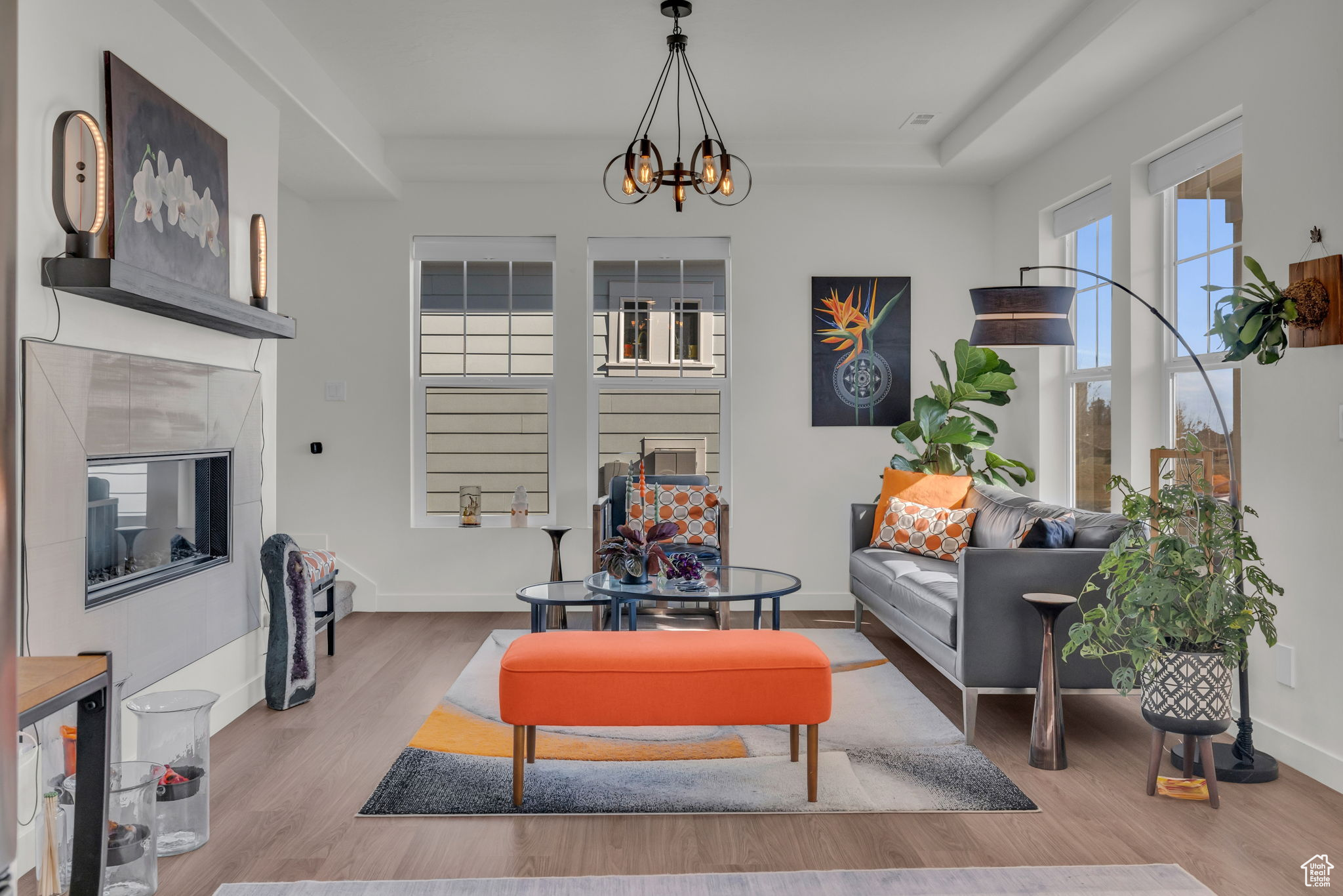 Living room featuring a tiled fireplace, hardwood / wood-style flooring, a tray ceiling, and a chandelier