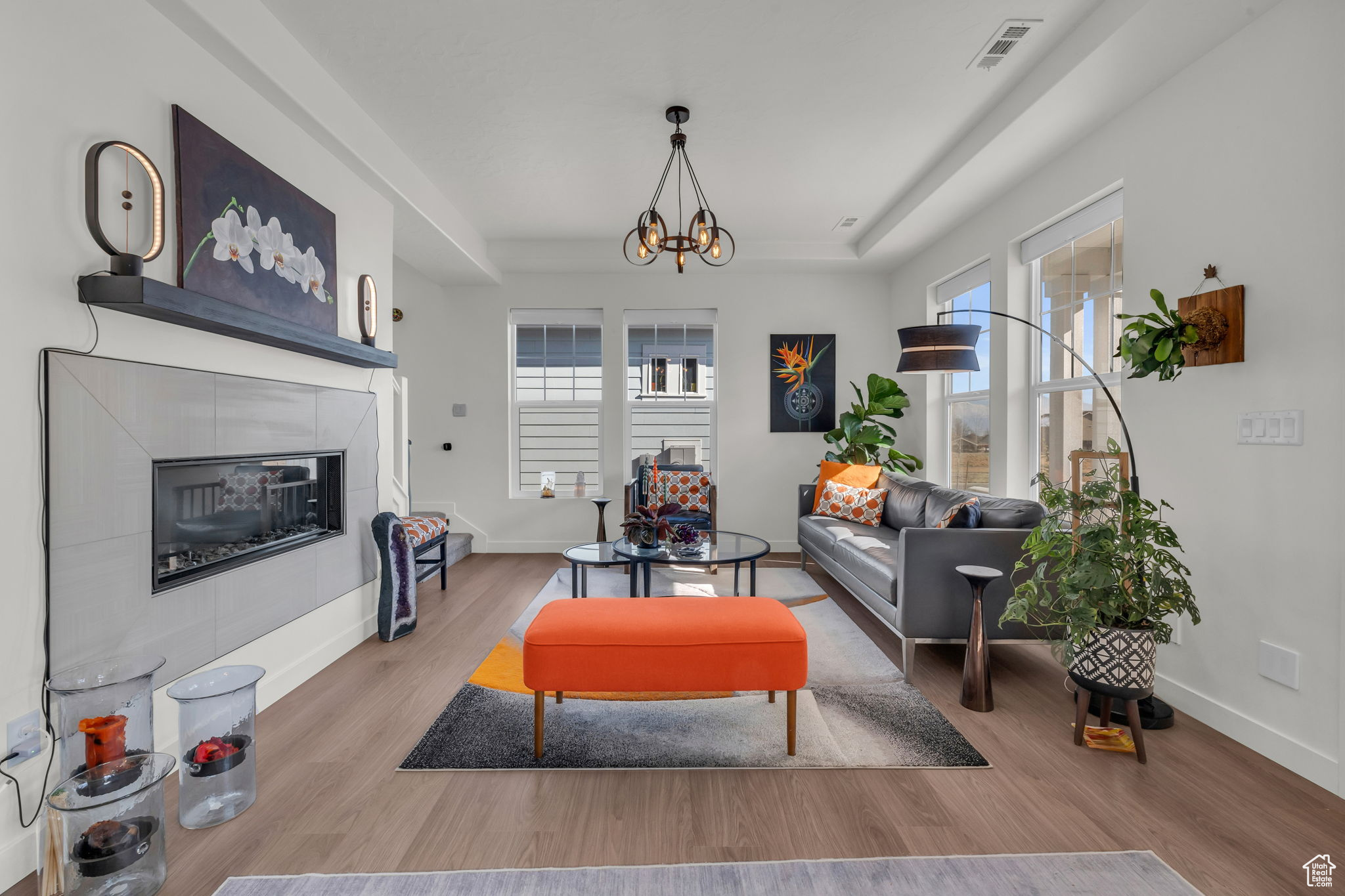 Living room featuring a tiled fireplace, a modern chandelier, and light hardwood / wood-style flooring