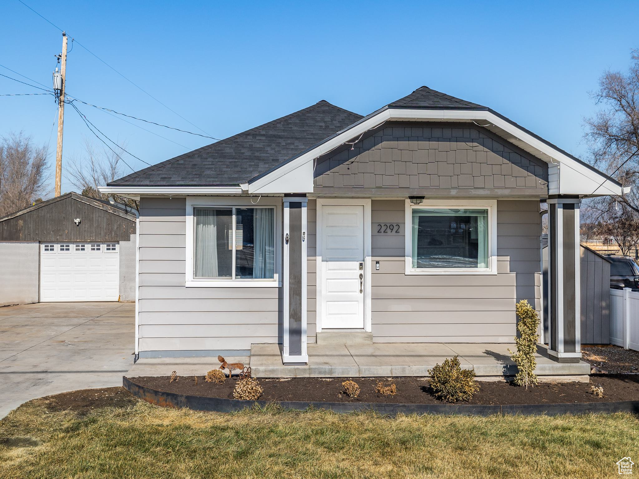 Bungalow-style house featuring a garage, an outdoor structure, and a front lawn