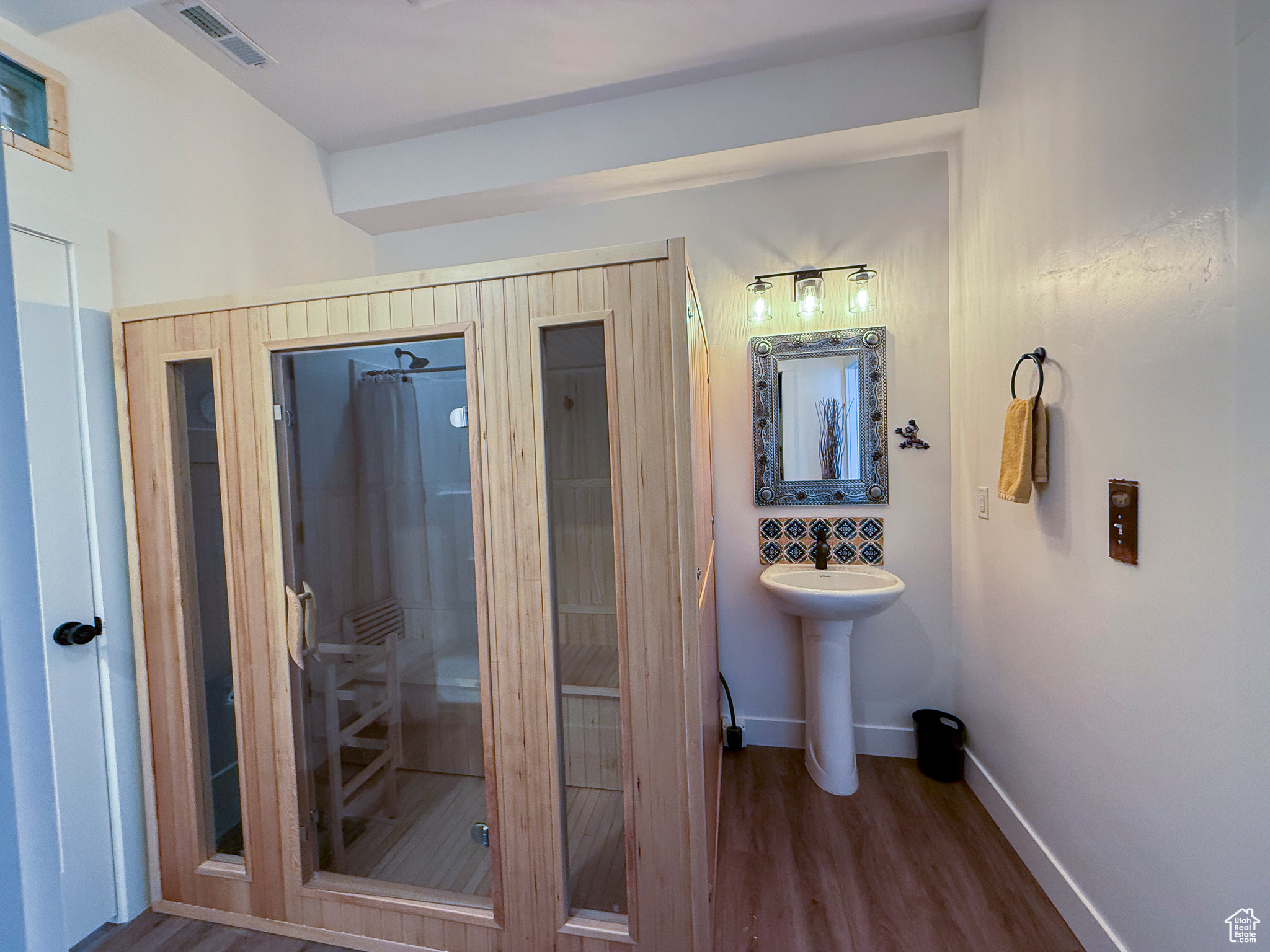 Bathroom with LVP floors, sink, shower with shower curtain and sauna